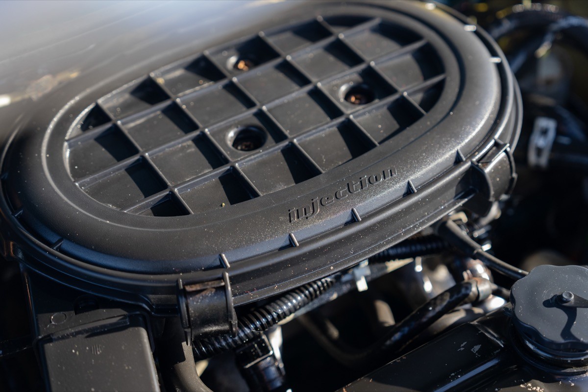 Close-up of a car engine component, featuring a sleek, black air intake manifold with a textured surface.