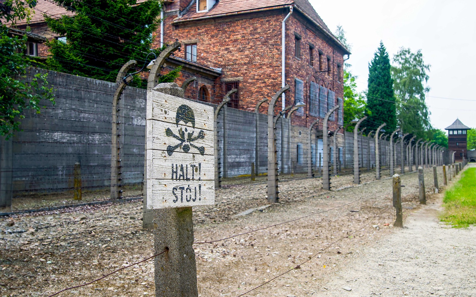 Wycieczka autobusowa z Krakowa do Muzeum Auschwitz-Birkenau, ogrodzenie i znak ostrzegawczy.