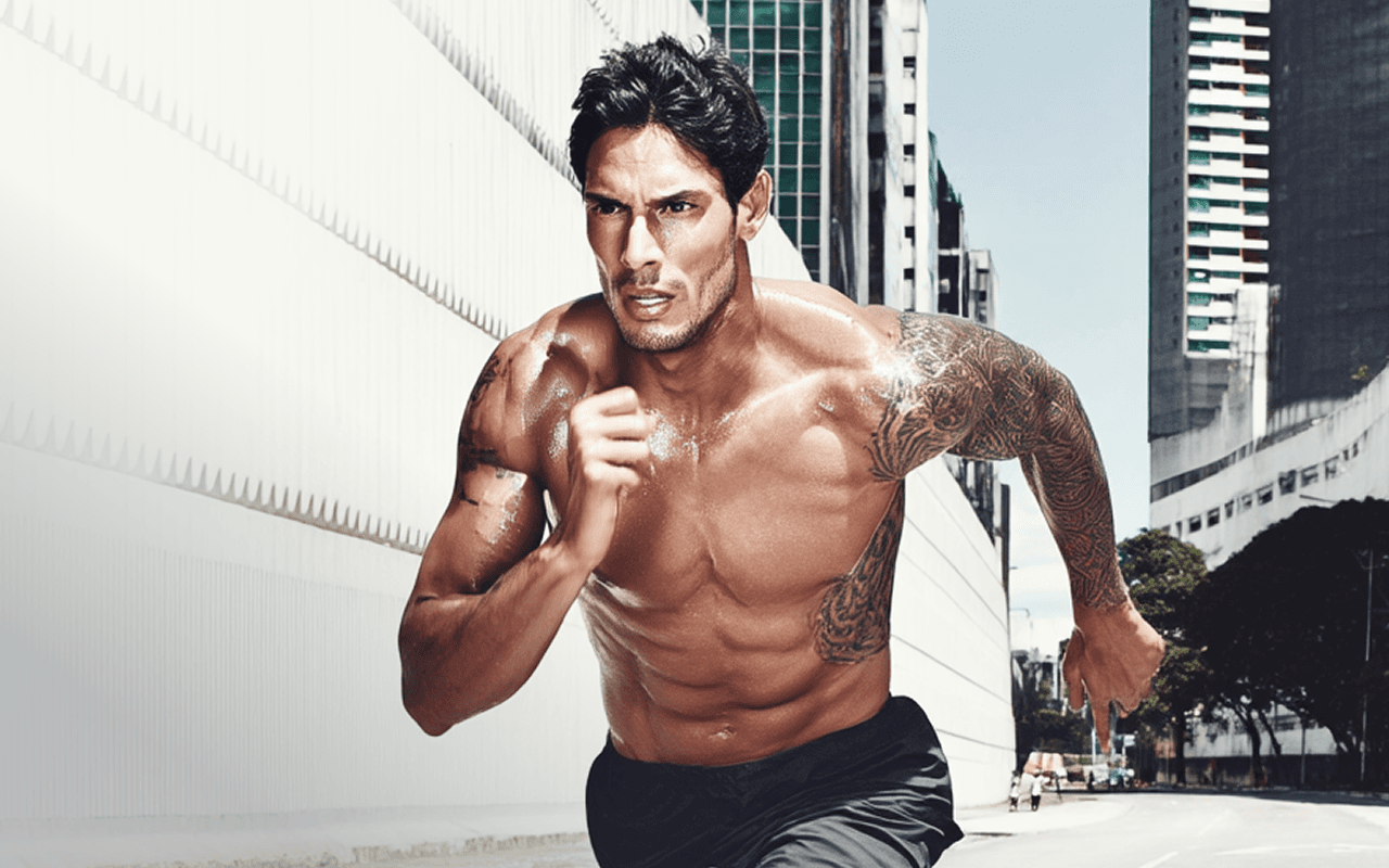 Muscular man running outdoors shirtless in an urban environment, showcasing strength, focus, and determination.