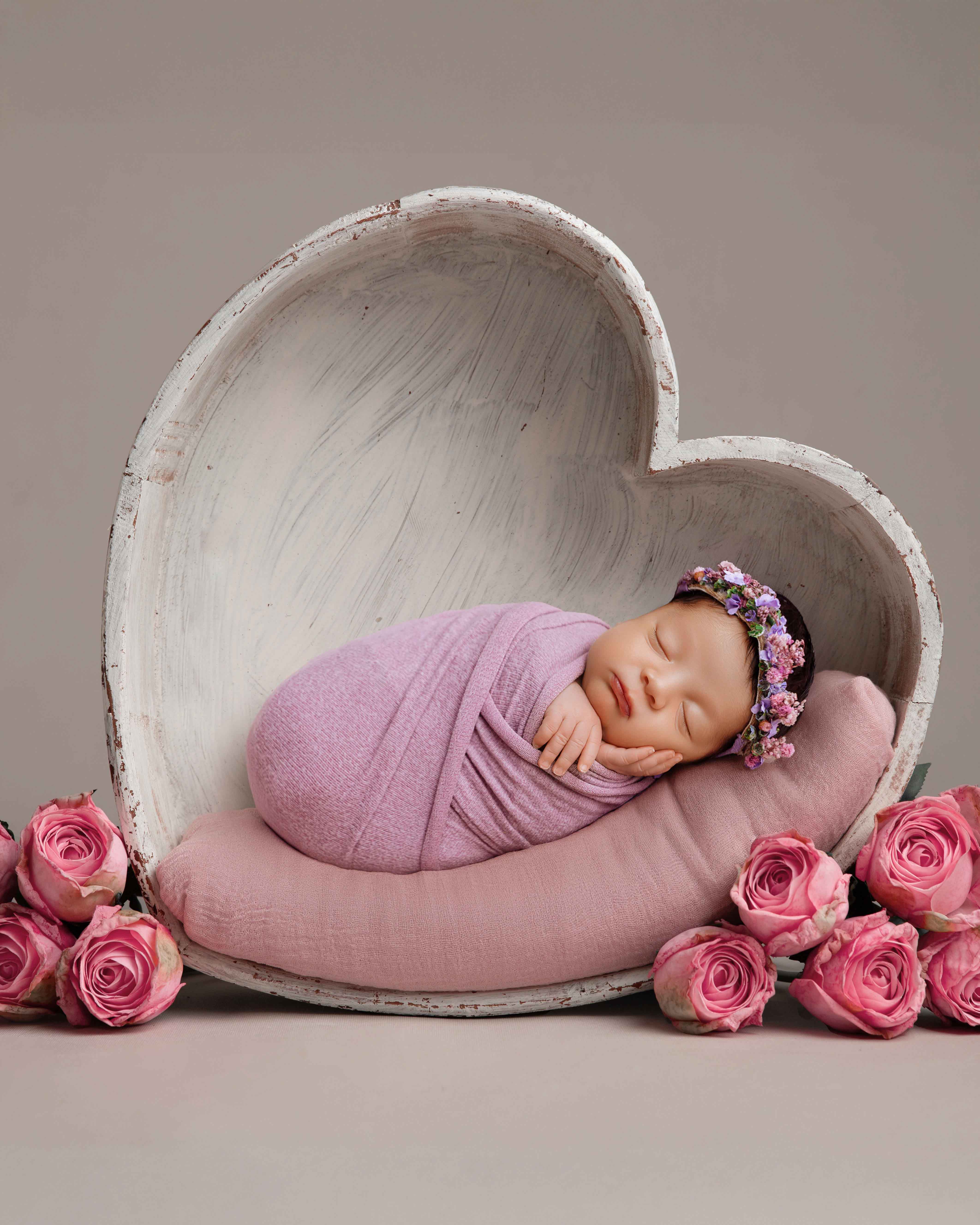 Newborn wrapped in pink swaddle — simple and timeless studio setup.