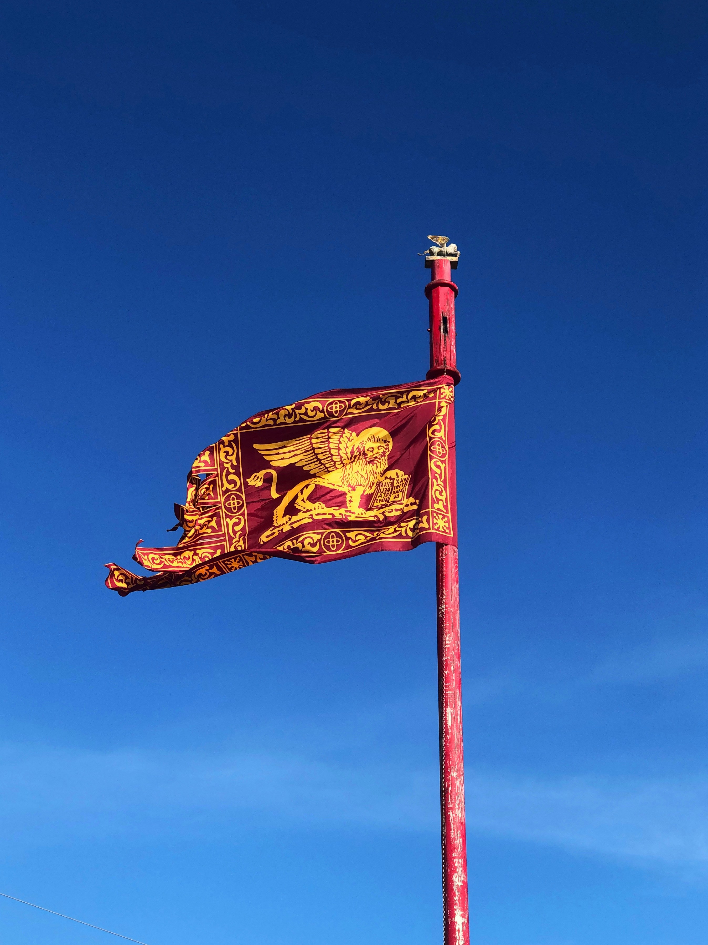 red and gold flag under blue sky during daytime