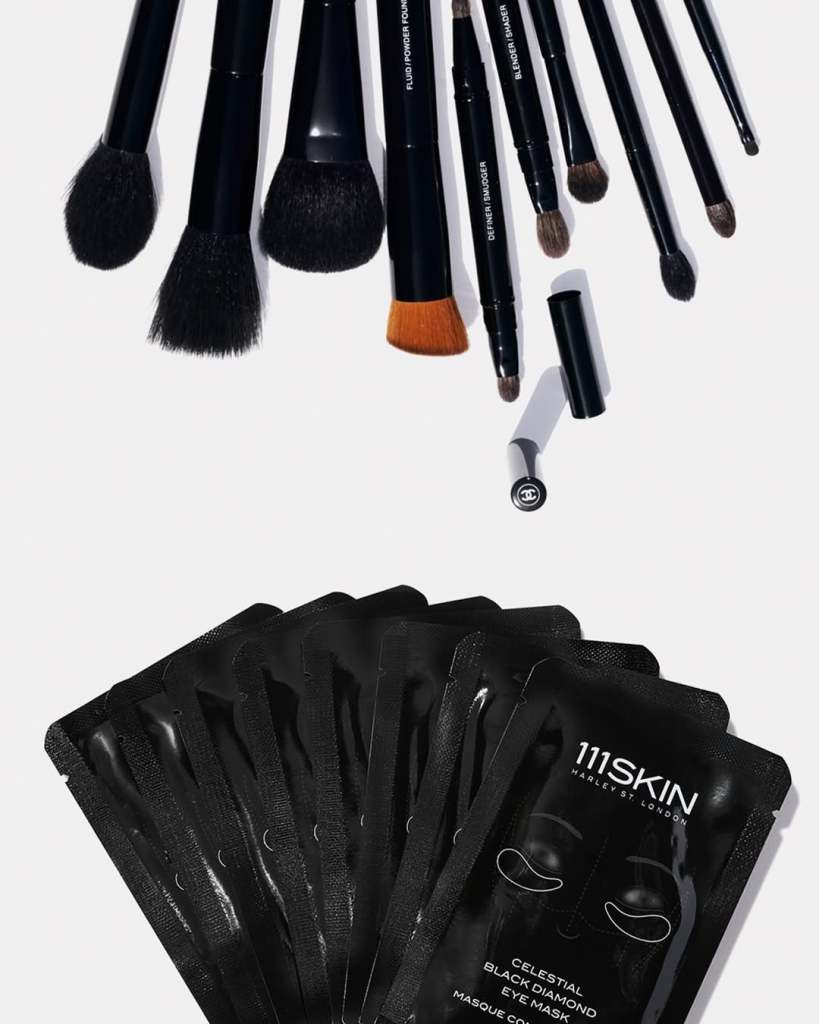 A collection of various makeup brushes arranged neatly on a white background, alongside several packets of 111SKIN Celestial Black Diamond Eye Mask.