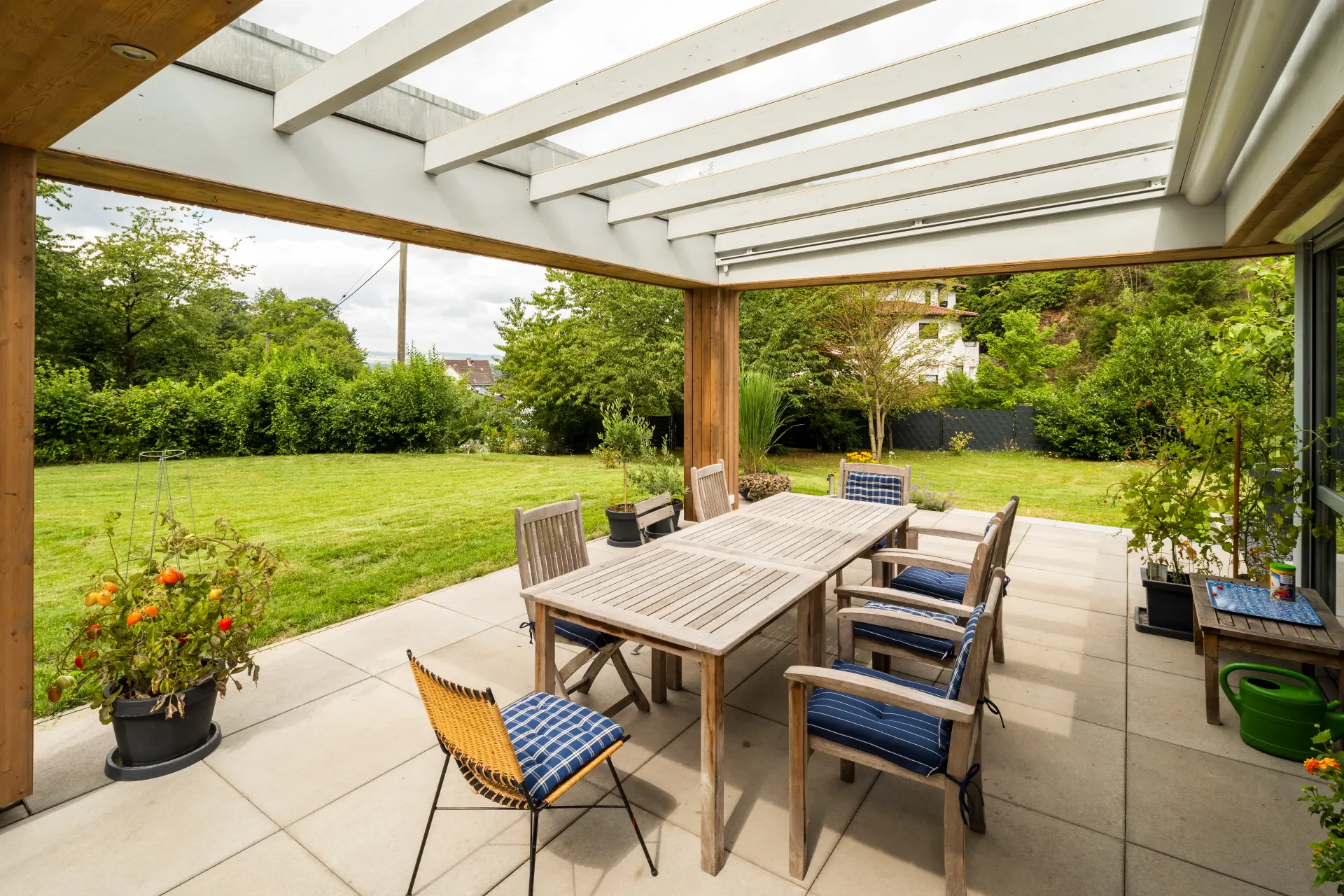 Überdachte Terrasse mit Esstisch und Sitzplätzen als neu gestalteter Außenbereich eines Hauses