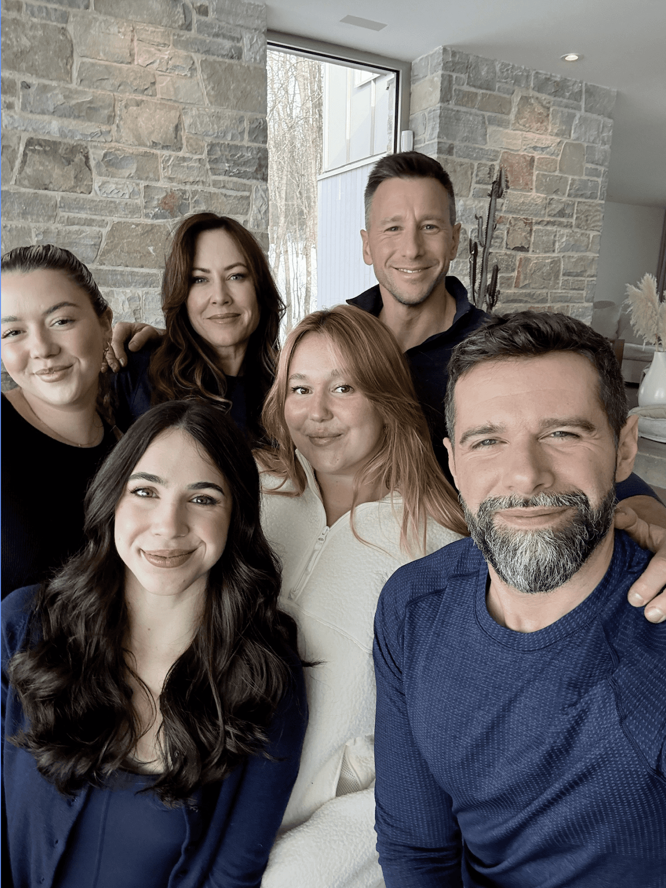 A person wearing glasses and a dark long-sleeve top sits confidently.