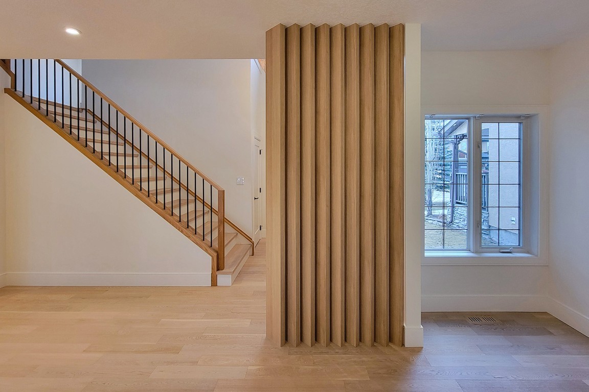 Image of KHD Homes interior design featuring wooden staircase, slatted room divider, and window in modern home layout.