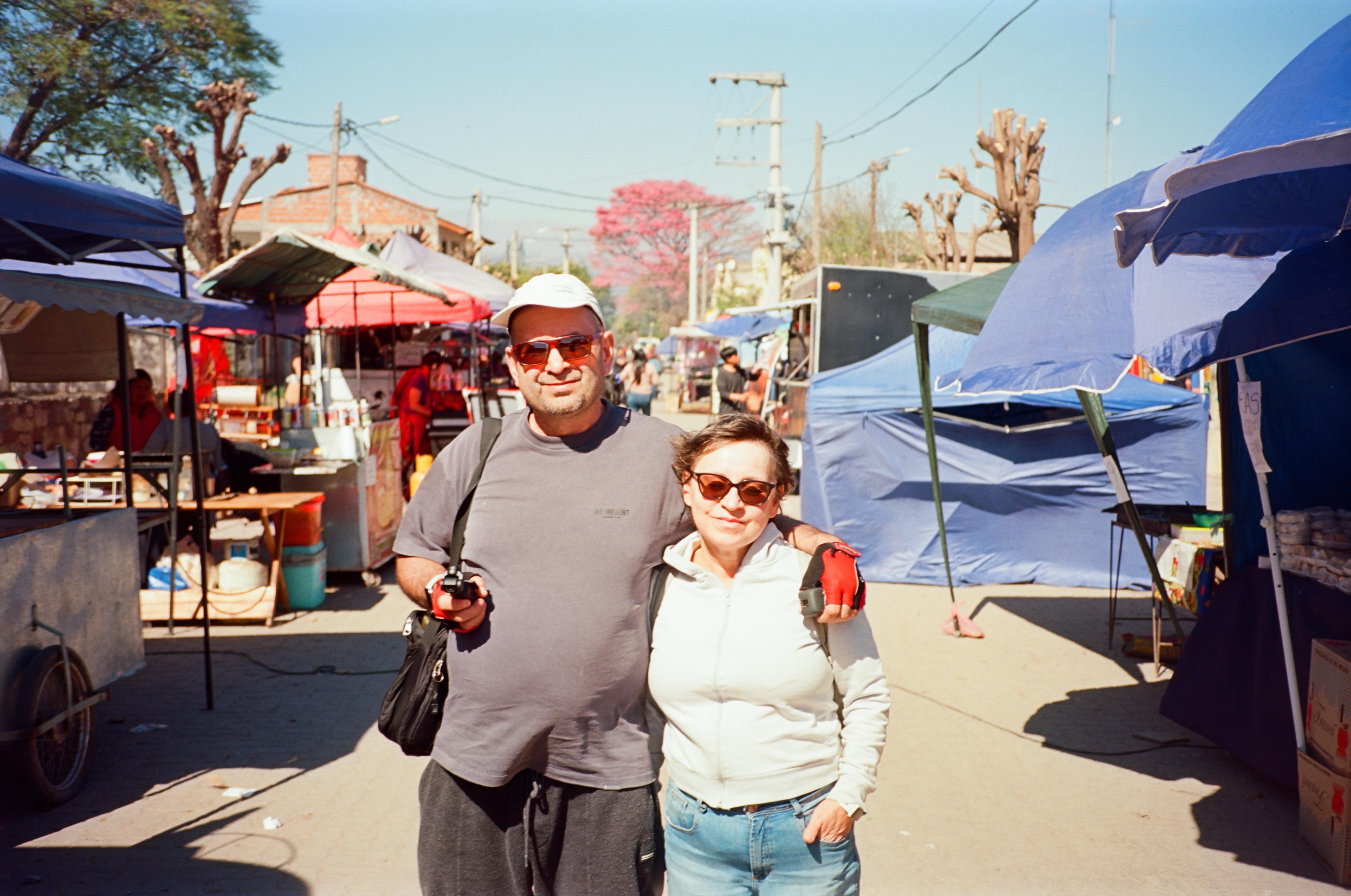 Mujer sentada sobre un tronco frente a una cascada doble en un bosque frondoso de Argentina.