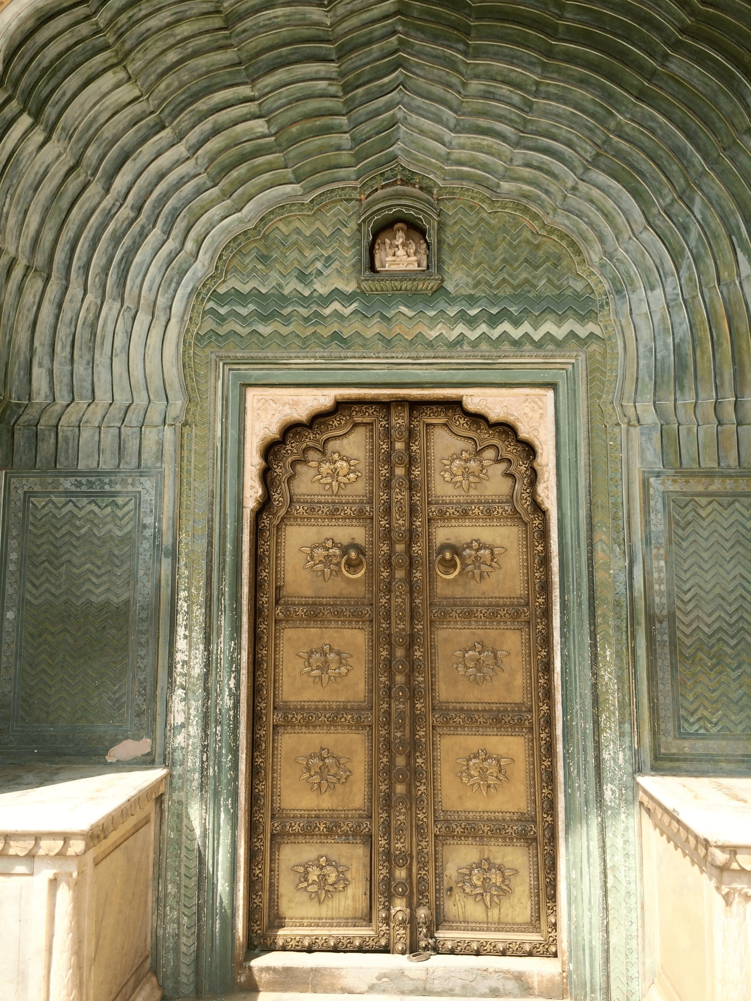 Smiling young man with short hair poses against a dark background, wearing a green button-up shirt.