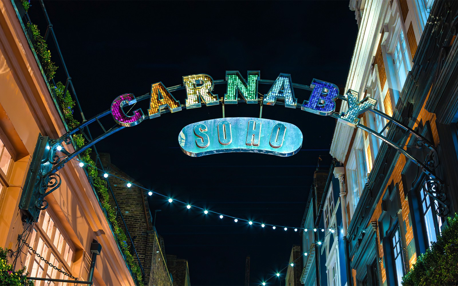 Carnaby Street sign illuminated at night in Soho, London.
