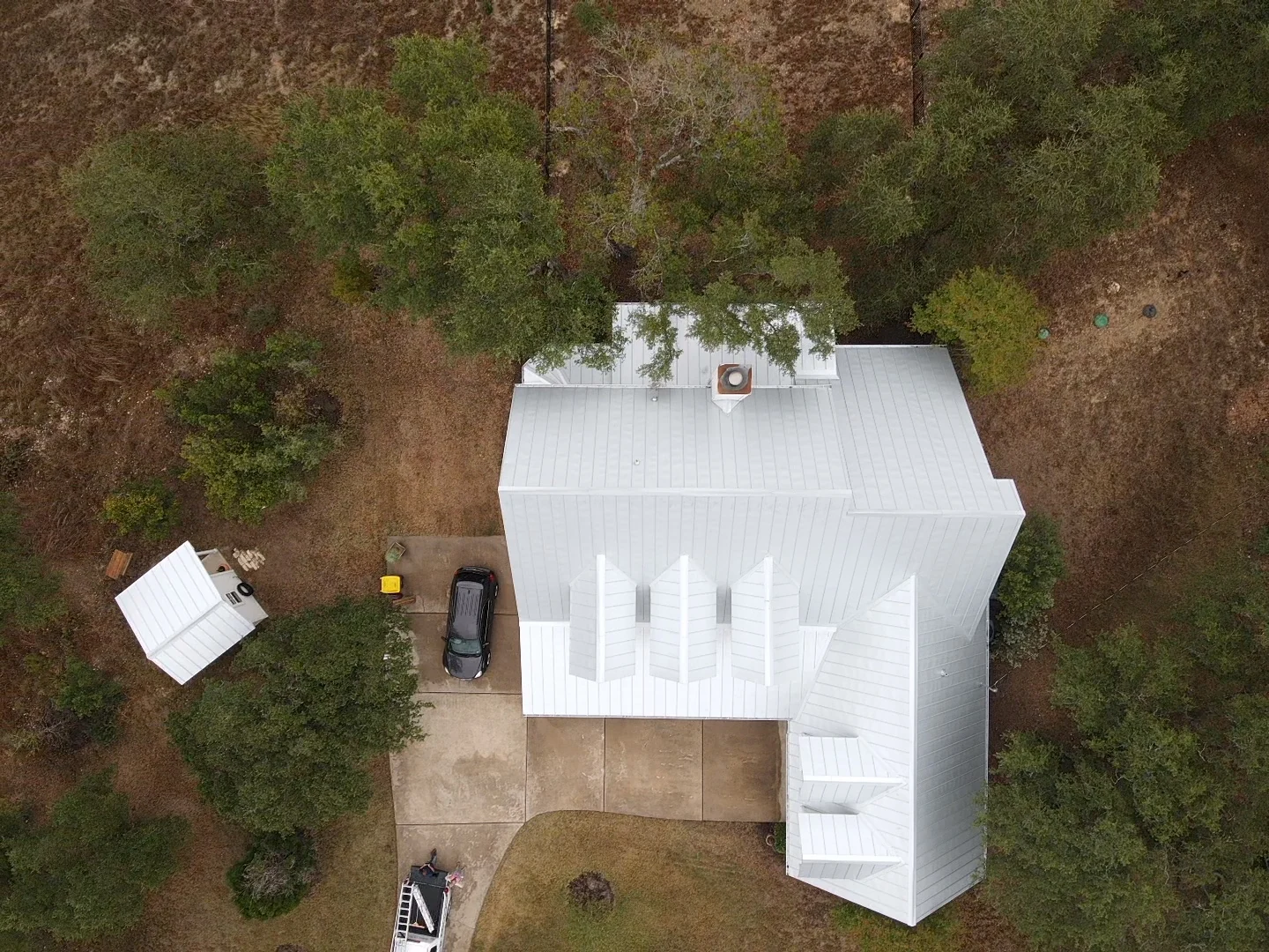 Finished silver-colored metal roof around five dormers, viewed from above.