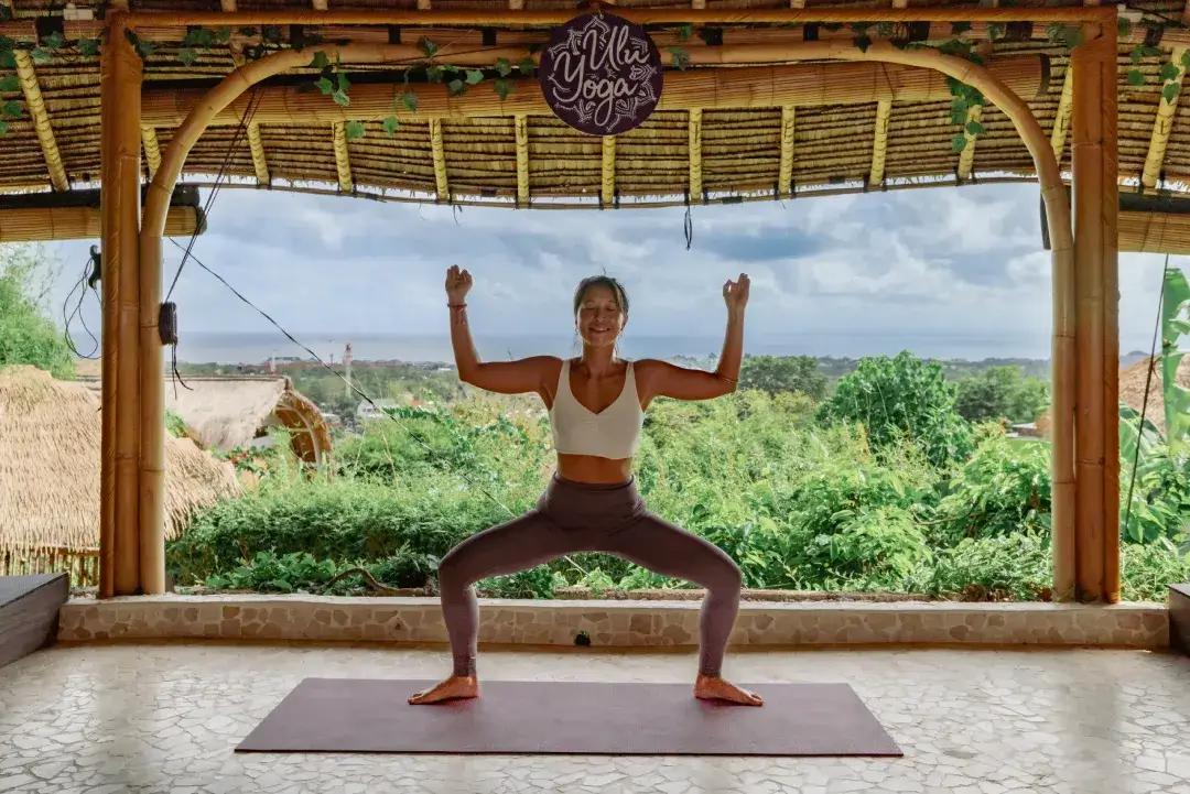 Expert instructor providing hands-on adjustments in Triangle pose during multi-style yoga teacher training in Bali
