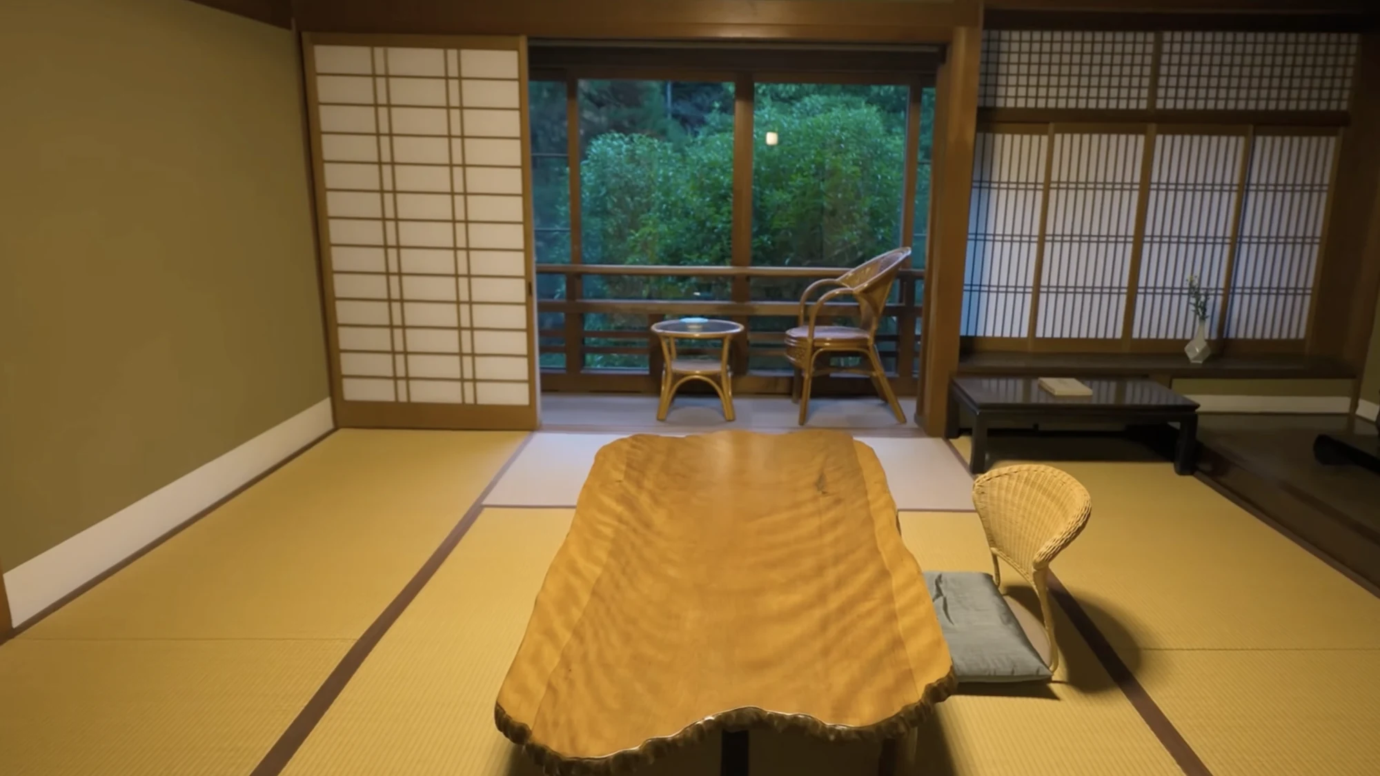 A tatami guest room in a Kinosaki inn with a thick live-edge timber table at its centre.