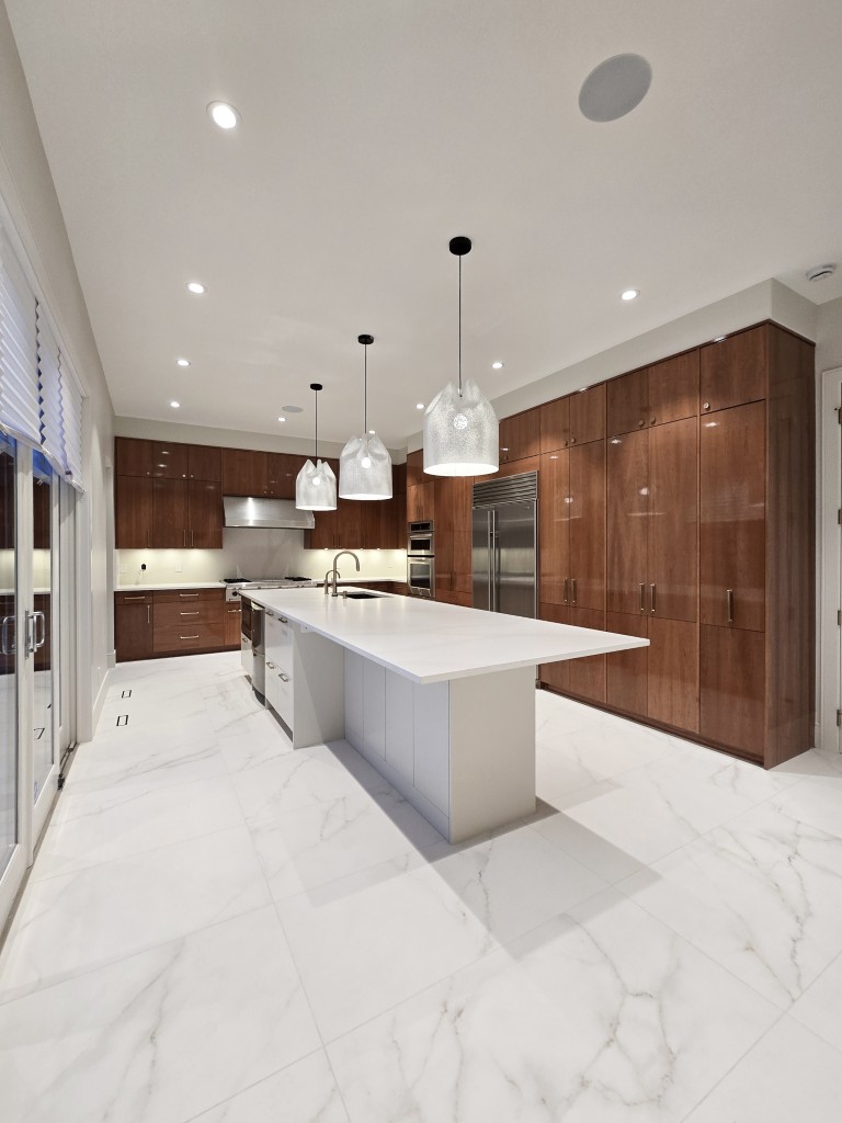 Image of Modern kitchen with large island, marble floors, and rich wood cabinets designed by KHD Homes.