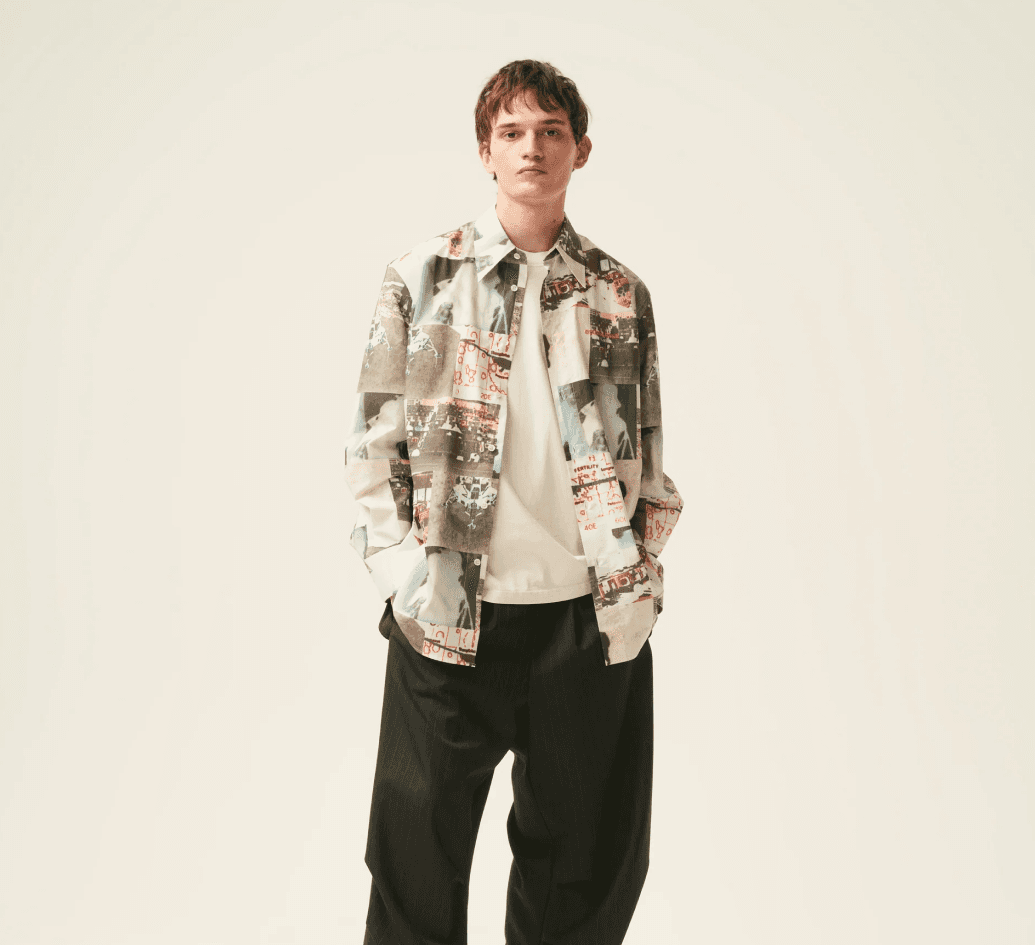 "Young man wearing a printed overshirt with graphic patterns and relaxed black trousers, showcasing contemporary urban fashion for men."