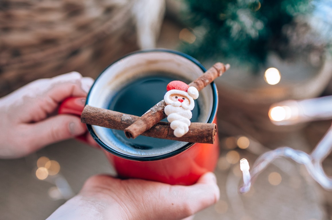 A christmas drink in a mug with a christmas tree in the background.