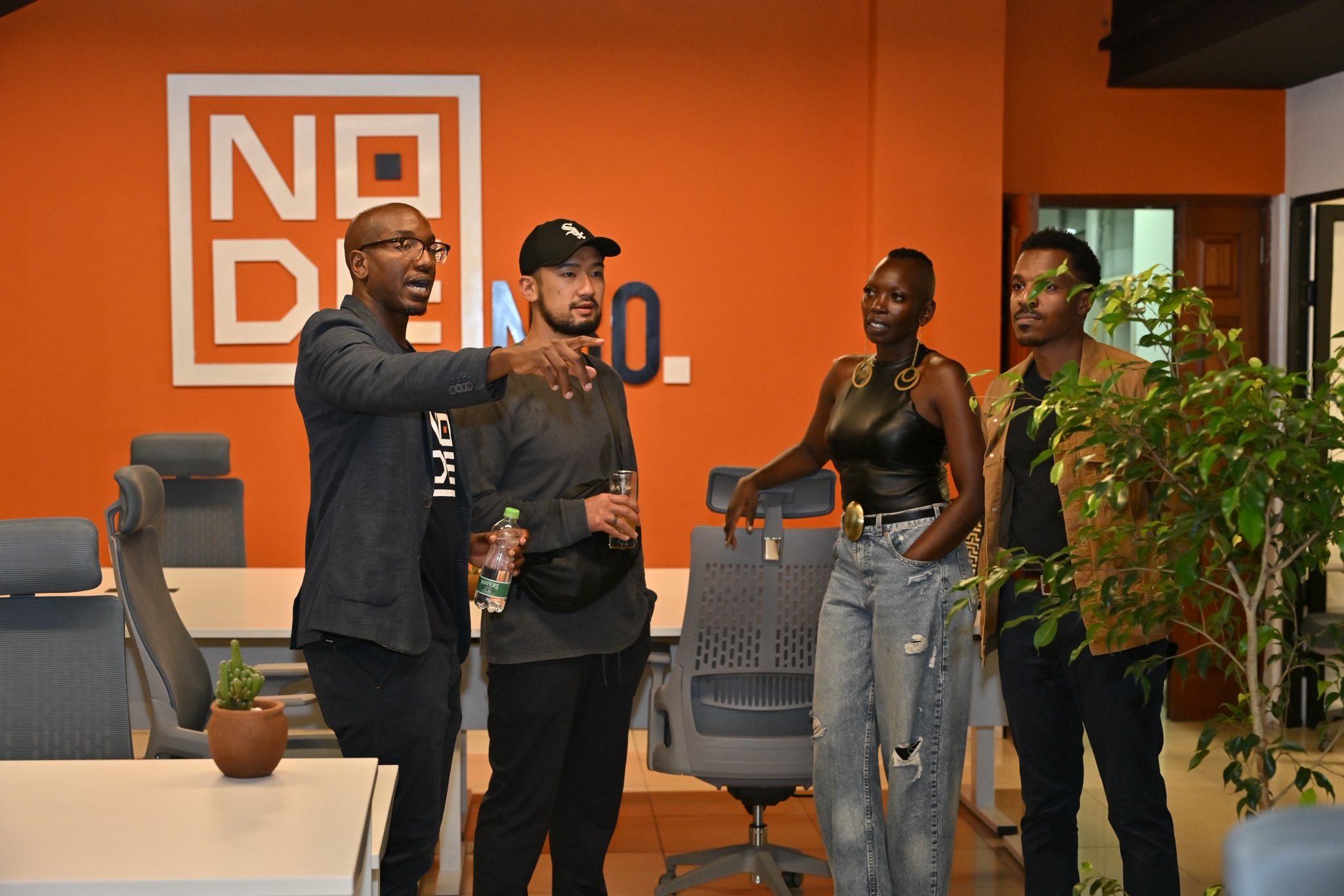 Visitors touring the Node NBO co-working facility in Gigiri, Nairobi, with the orange-branded Node NBO logo on the wall