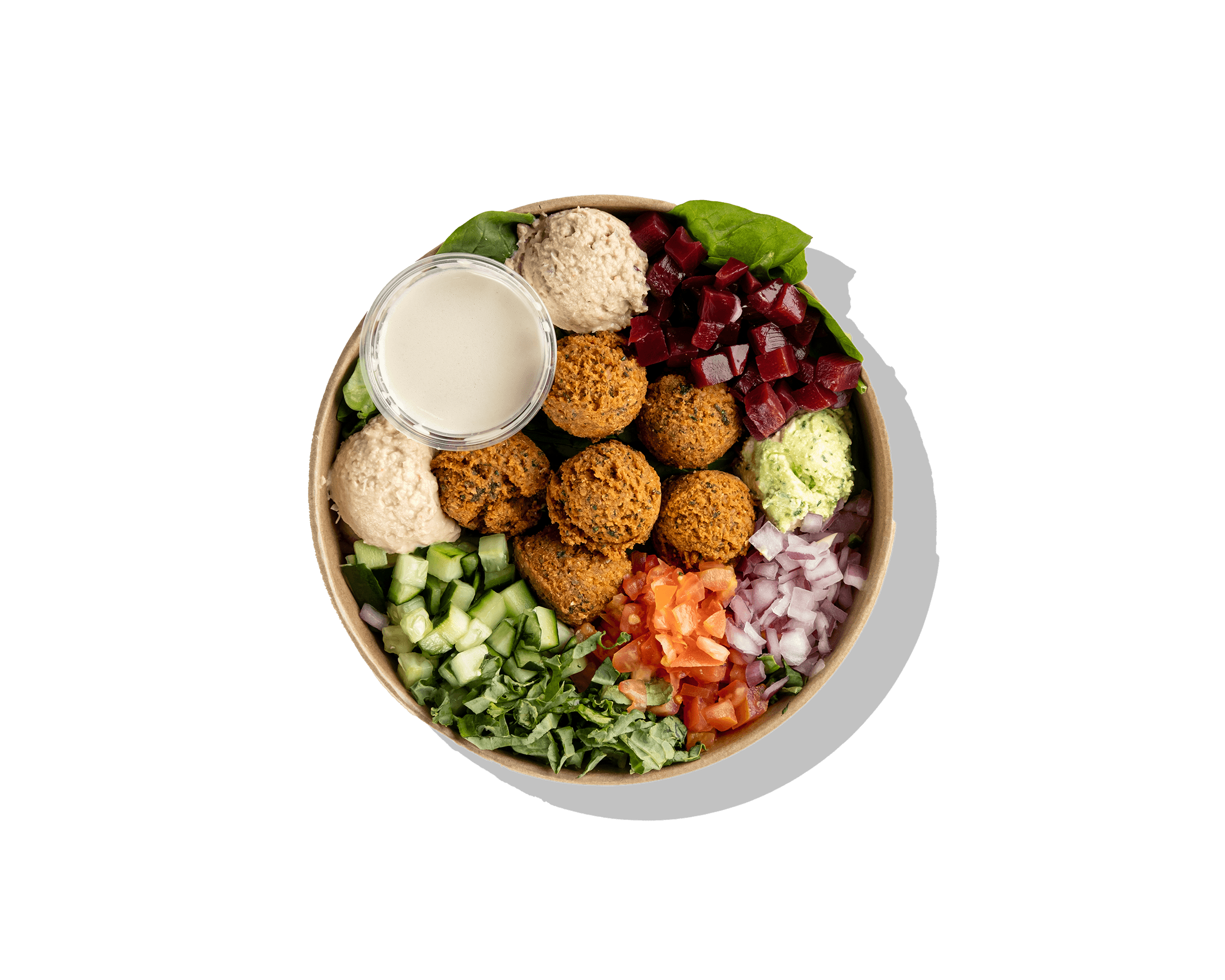 Top-down view of a customizable Mediterranean grain bowl with greens, protein, and assorted toppings.