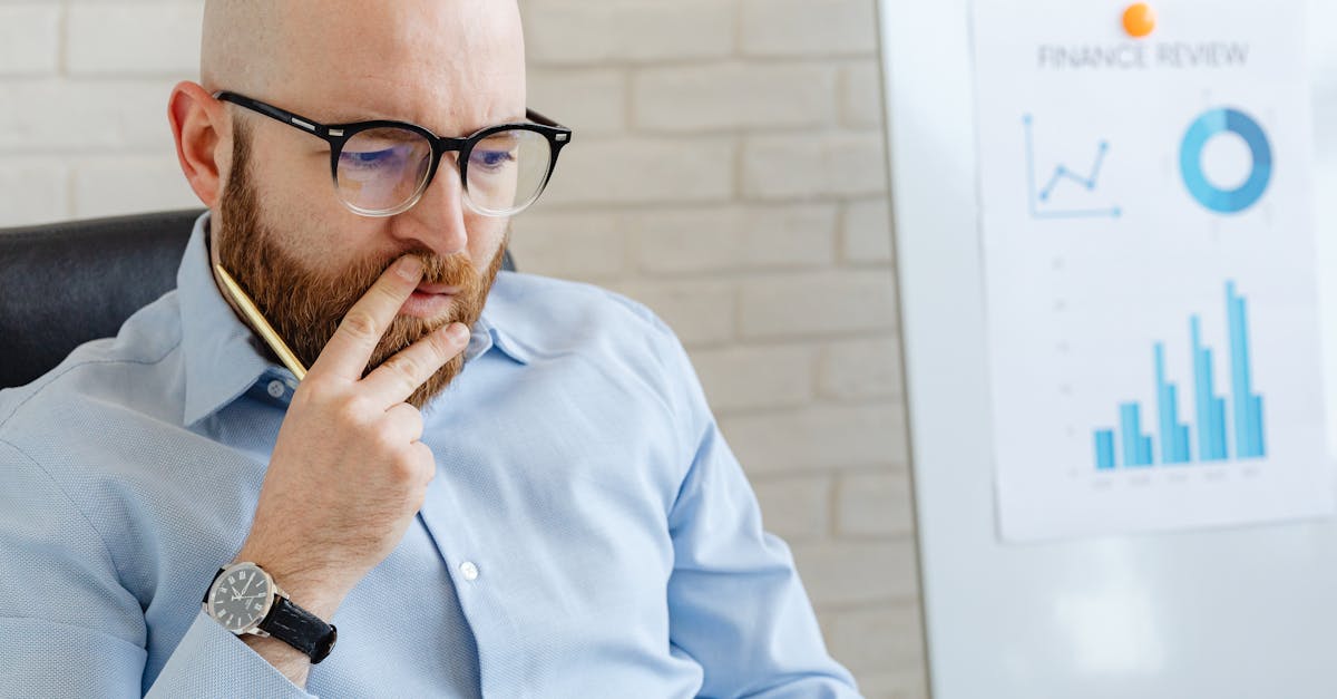 Business analyst in a blue shirt analyzing financial charts on a whiteboard.
