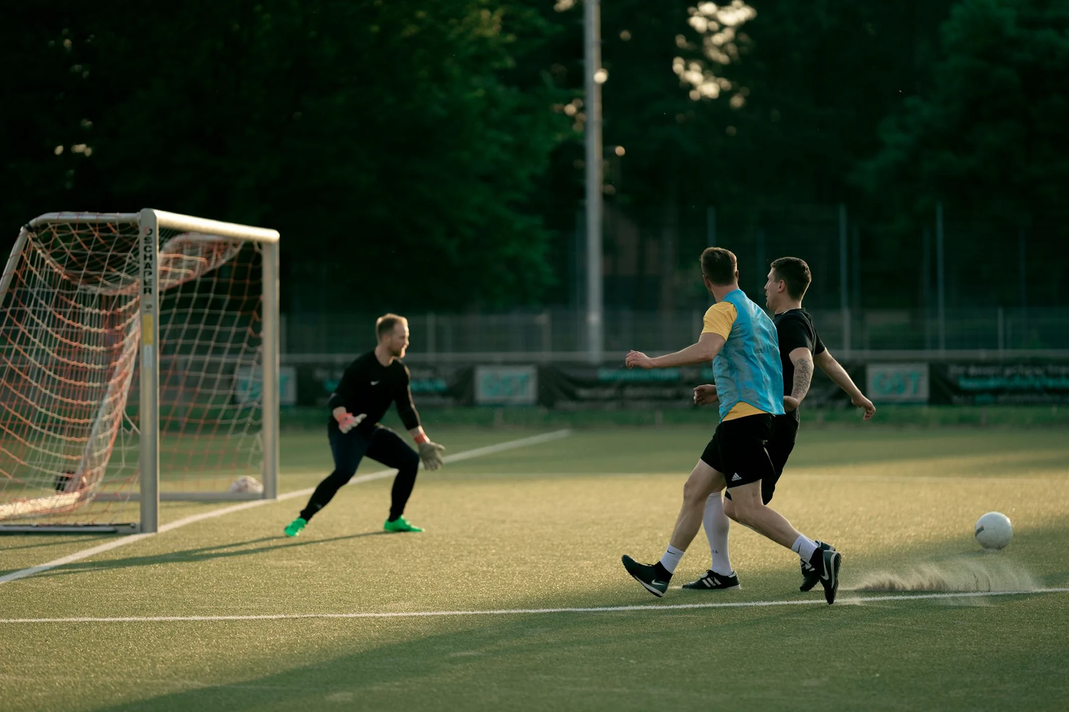 Soccer goal and players on an artificial-turf field at night