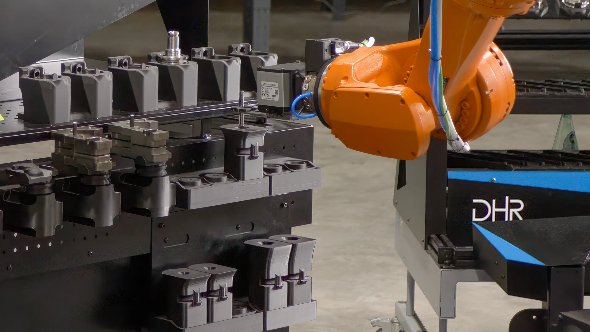 A robotic arm is precisely inserting a cutting tool into a collet, aided by a guiding funnel to ensure accurate alignment. Automation by DHR Engineering
