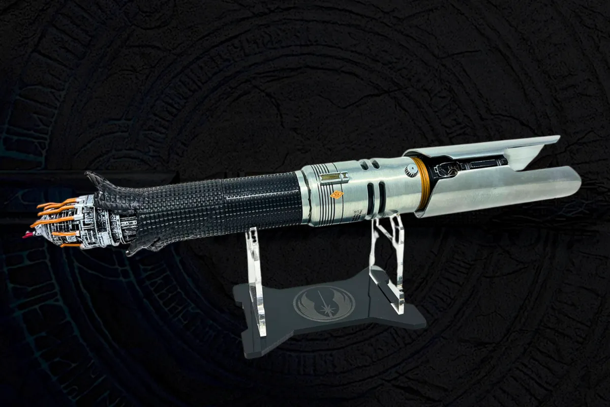 A high-quality replica of Cal Kestis’ lightsaber from Star Wars Jedi: Fallen Order and Jedi: Survivor, displayed on a custom stand featuring the Jedi Order symbol. The hilt has a battle-worn design, with one end appearing damaged and exposing intricate wiring, while the other end features a metallic, double-bladed emitter.