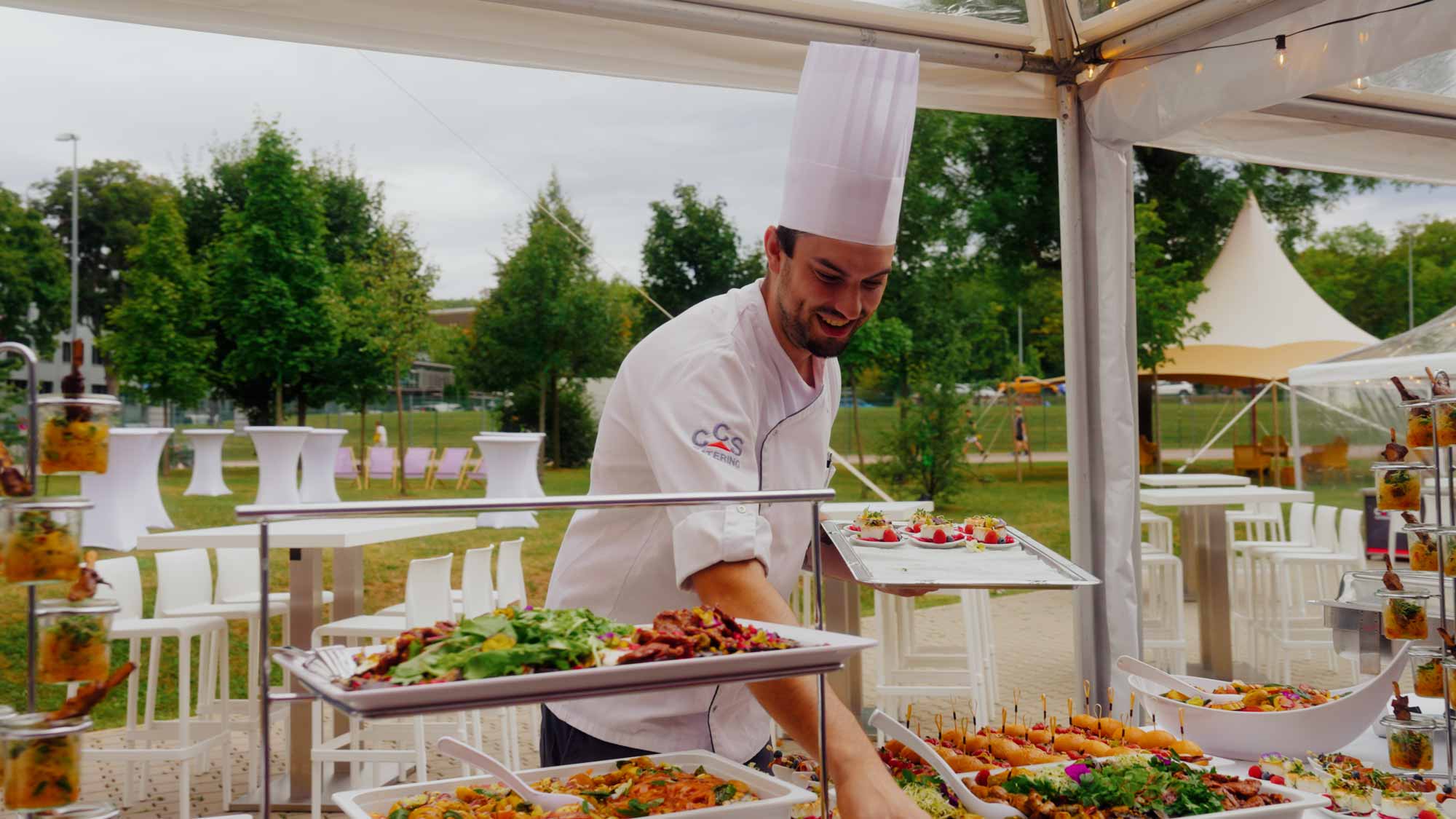 Chef arranging a colorful buffet outdoors, ideal for filmproduction ads and social media campaigns focused on brand storytelling, steigerwaldstadion