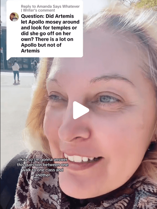 A smiling man with glasses, curly hair, wearing a maroon hoodie, poses against a dark background.