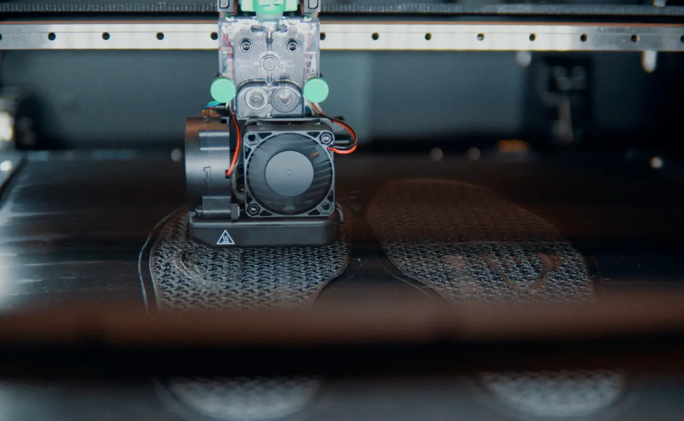 Robotic gripper assembly with visible cables and a circular fan sits on a textured track, illustrating robotics branding in an industrial workflow.
