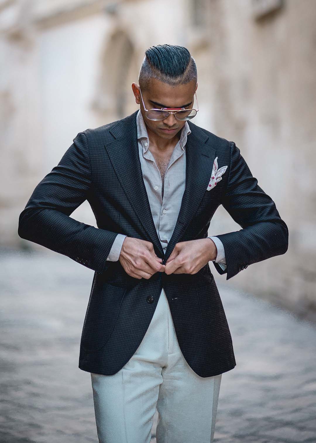 A refined man buttoning his tailored black jacket in an Italian street, representing Don Marrón’s commitment to Italian craftsmanship and modern menswear elegance.
