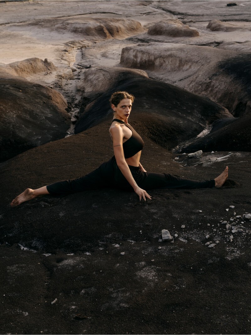 Blertë Dibrani im Spagat auf einem dunklen Felsen