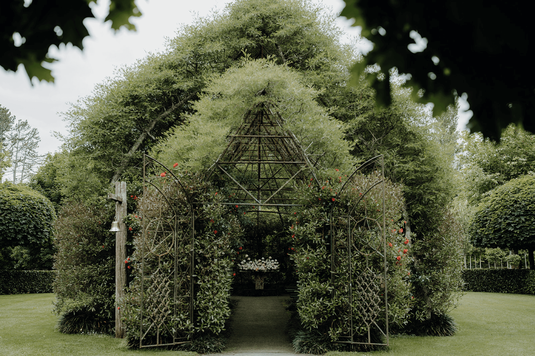 A green, white and gold minimalistic, architecturally designed kitchen with a women walking behind the kitchen bench, blurred