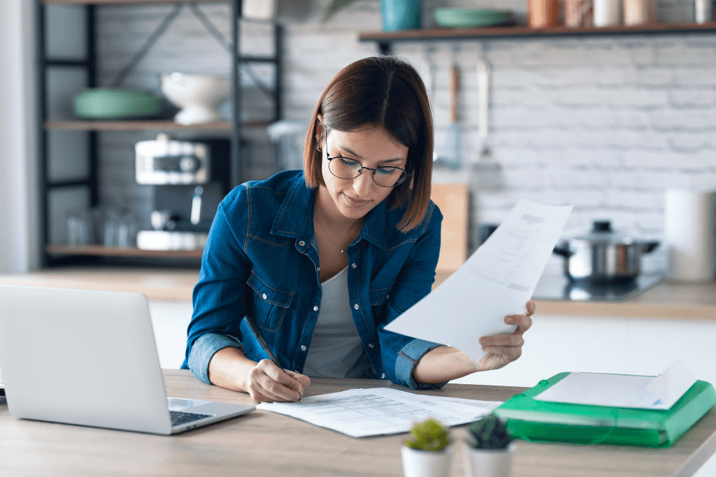 woman working with computer while consulting documents