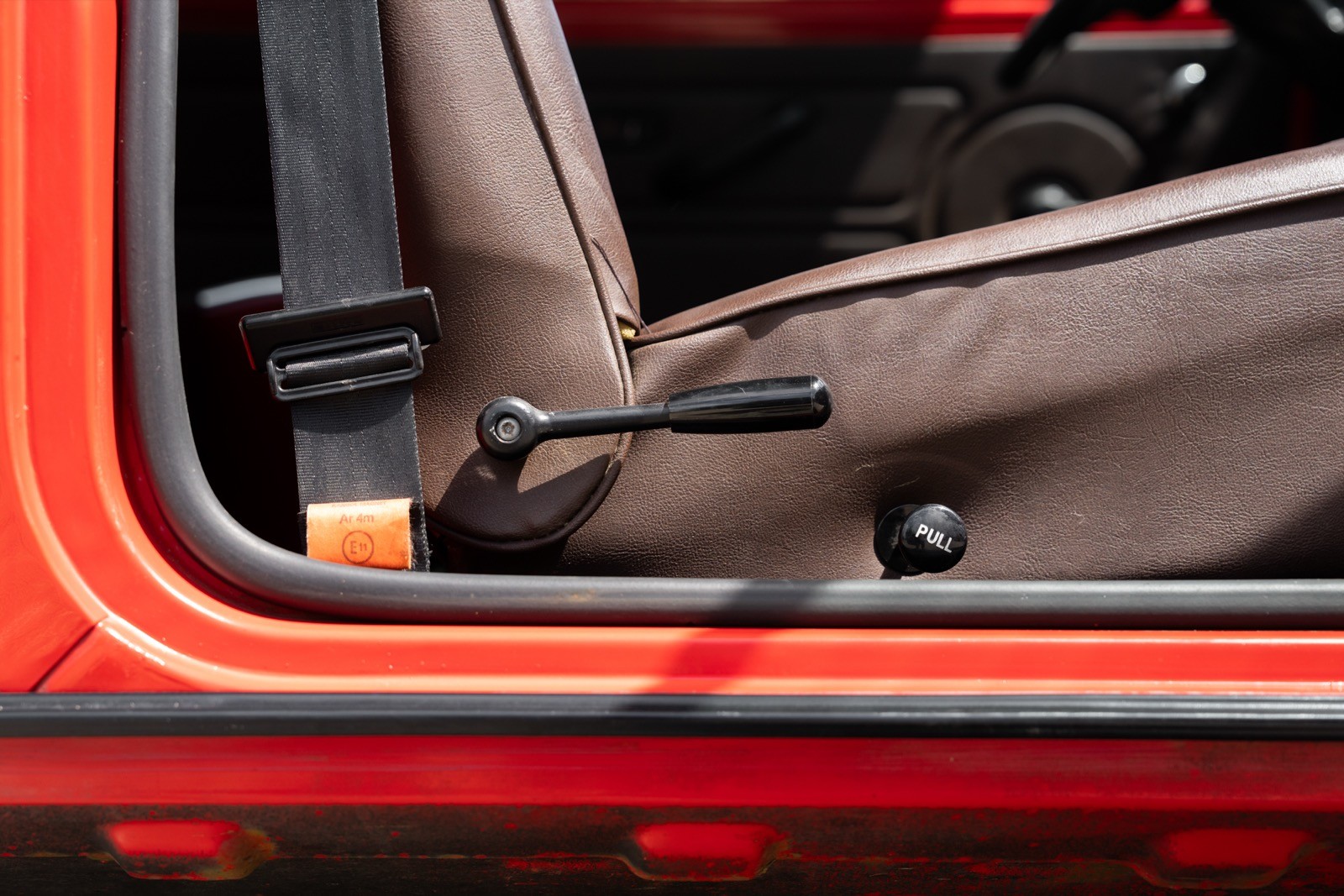 Close-up of a vehicle's interior door panel with a focus on the handle and trim details, highlighting texture and design.