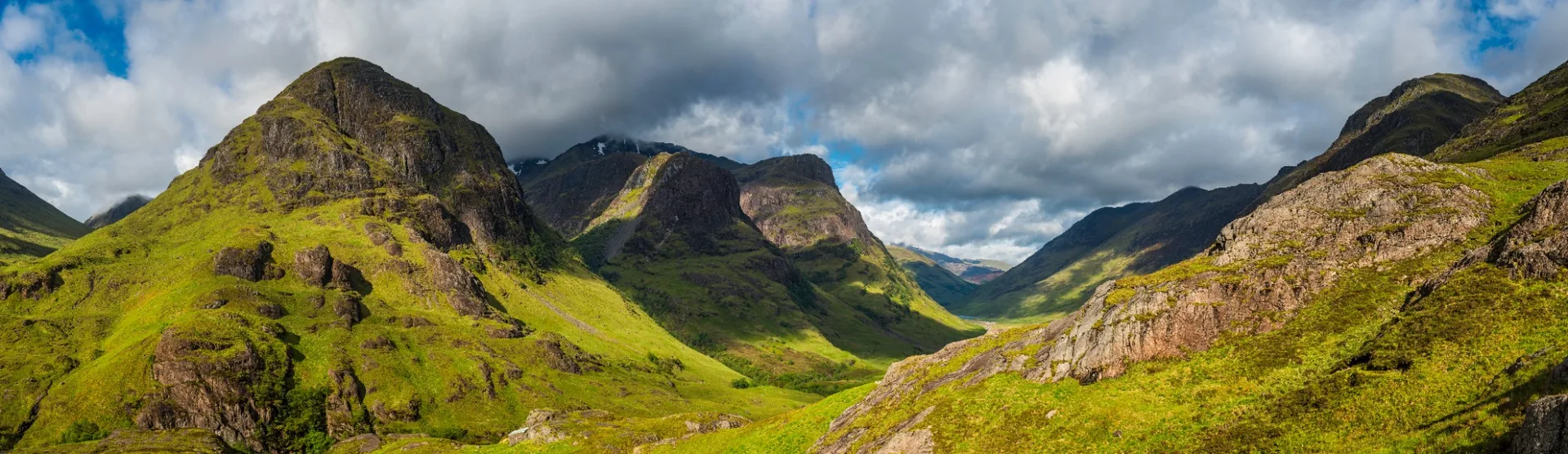 Panoramic view of Glencoe’s mountains and valley beneath cloud.