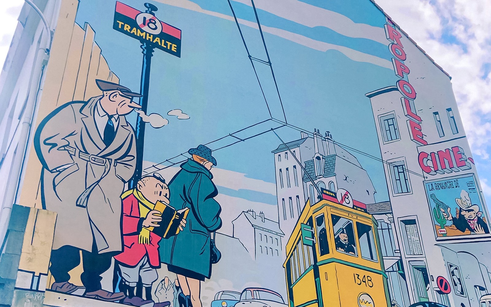 Brüsszeli falrajz, amely képregényhősöket és egy villamost ábrázol, ahogy a hop-on hop-off buszos városnézés során látható.
