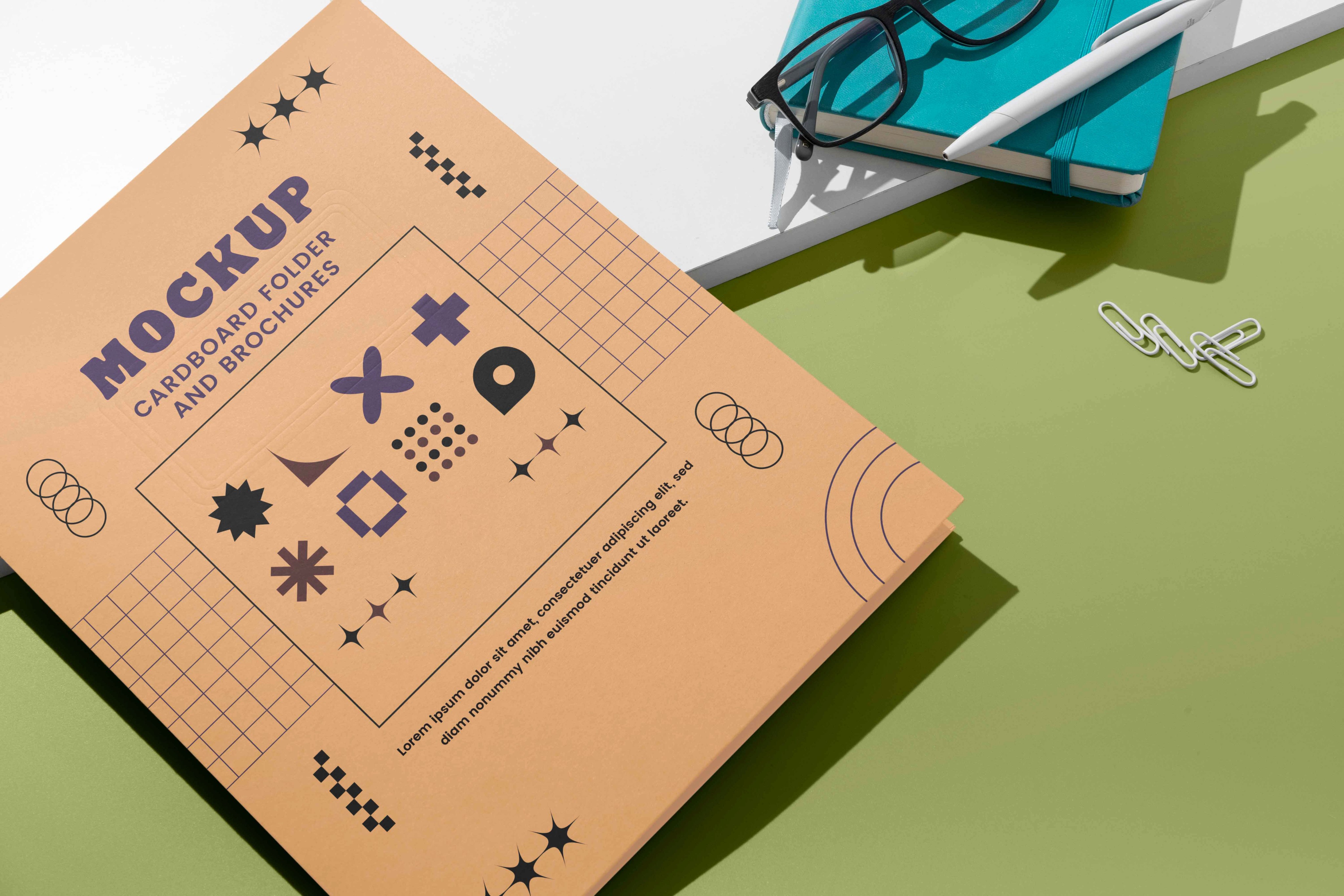 Top-down view of a peach-colored notebook featuring abstract geometric icons and patterns, placed on a green surface next to glasses and a notepad, representing platform architecture and multi-role design.  5