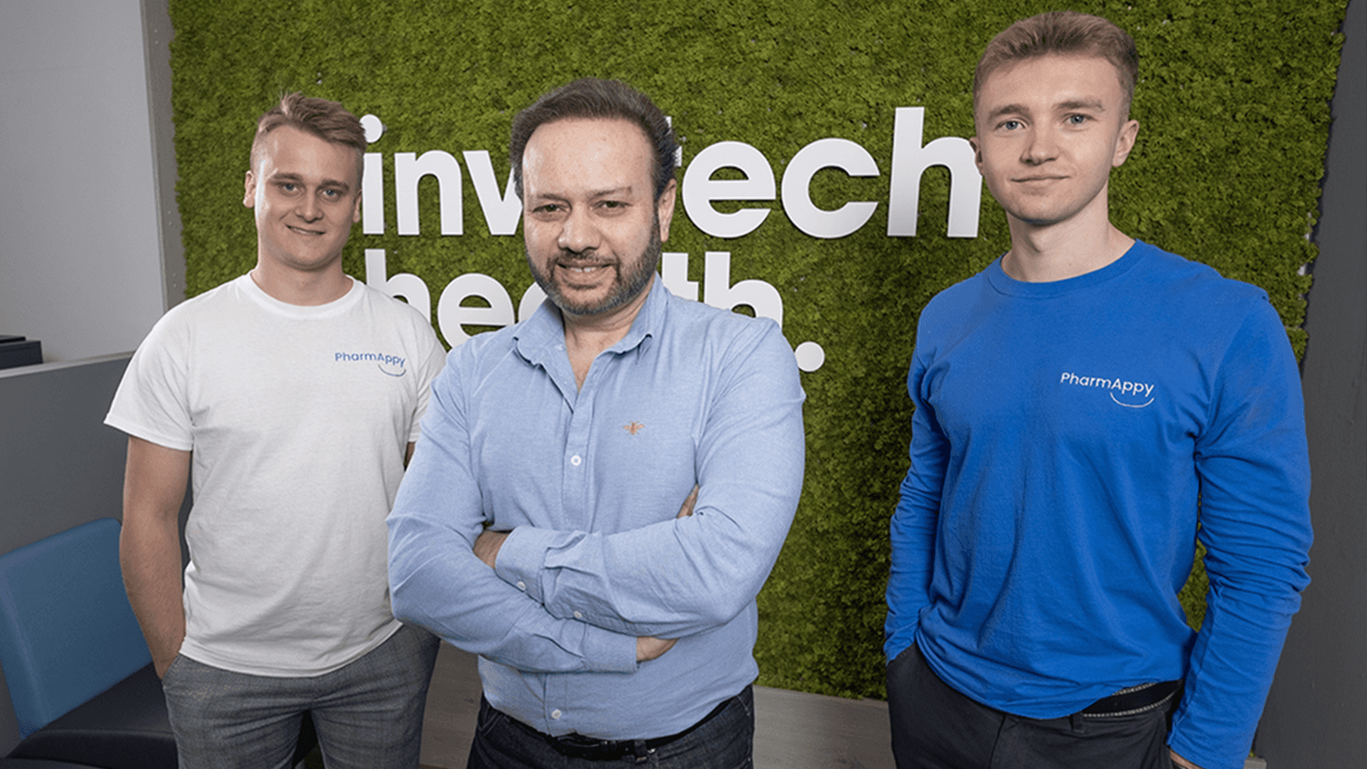 Tariq Muhammad, CEO of TITAN PMR, standing with two PharmAppy team members in front of an Invatech Health wall, representing collaboration and digital innovation in pharmacy