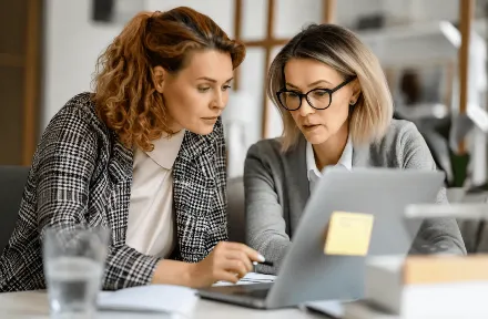 Two business professionals collaborating at a laptop while discussing affiliate partnerships.