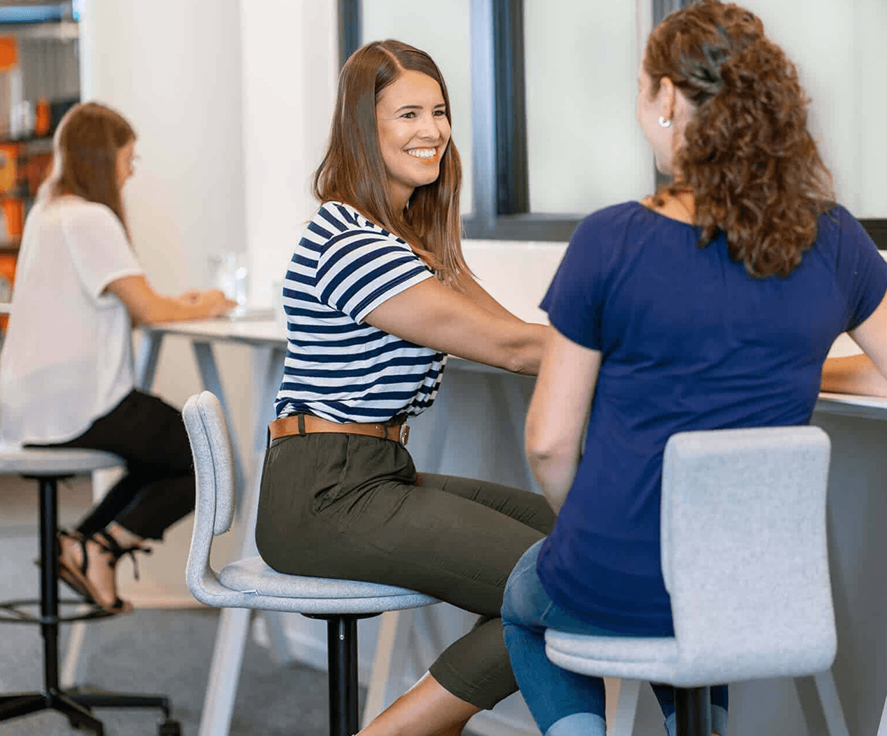 Two female Sovendus employees chatting at a table in the Sovendus office
