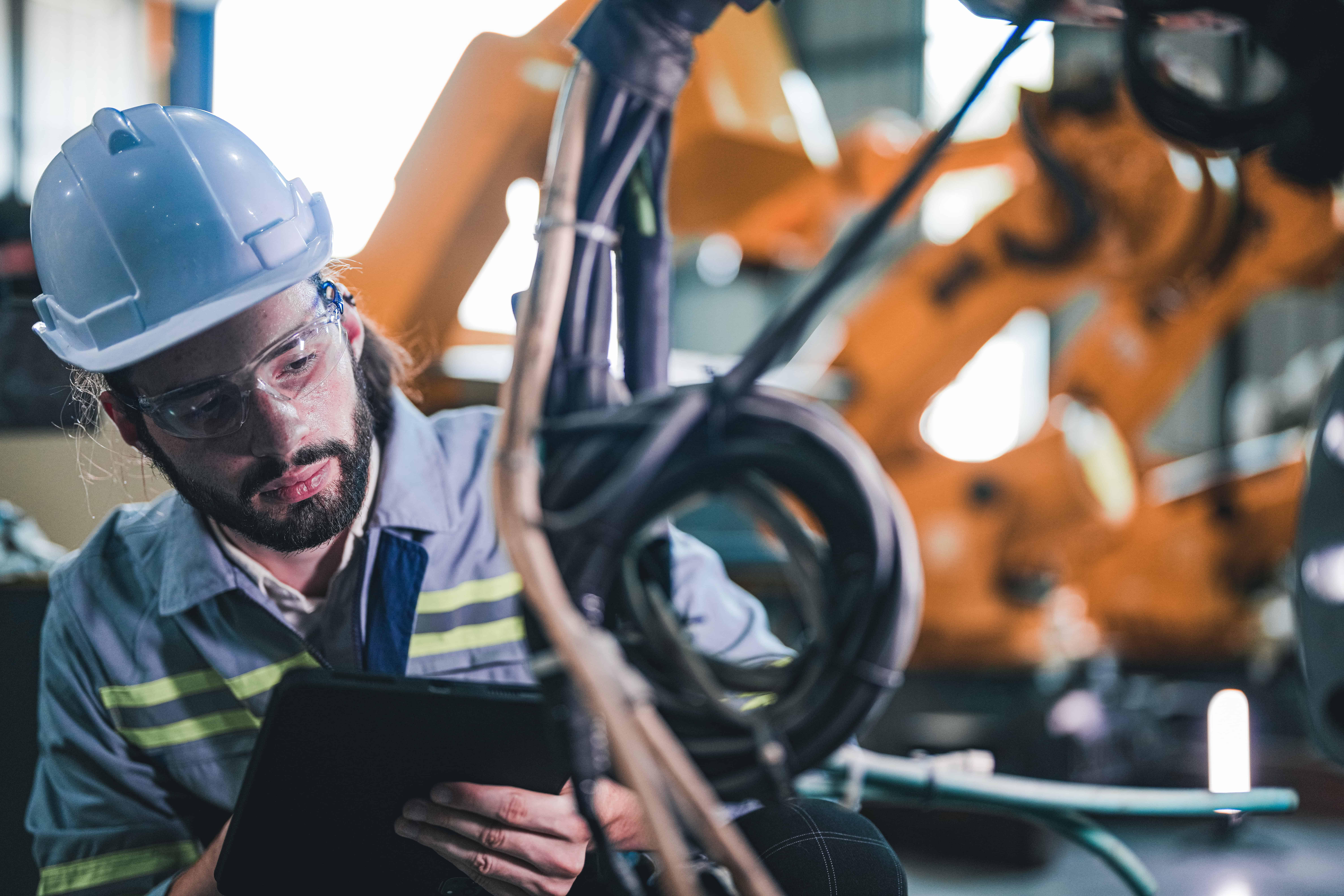 Mine worker examing and performing maintenance on equipment wearing correct PPE