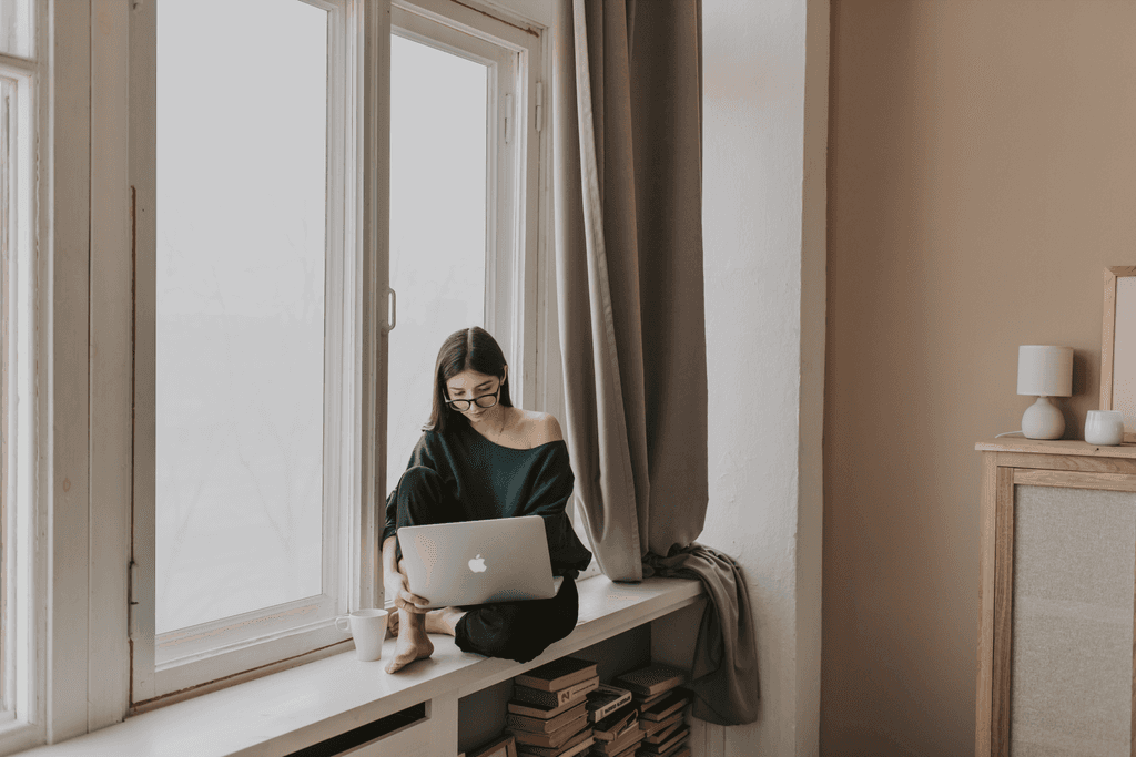 A person working on a laptop near a window with Rapid Glass smart film, blocking harmful UV rays while allowing natural light indoors.