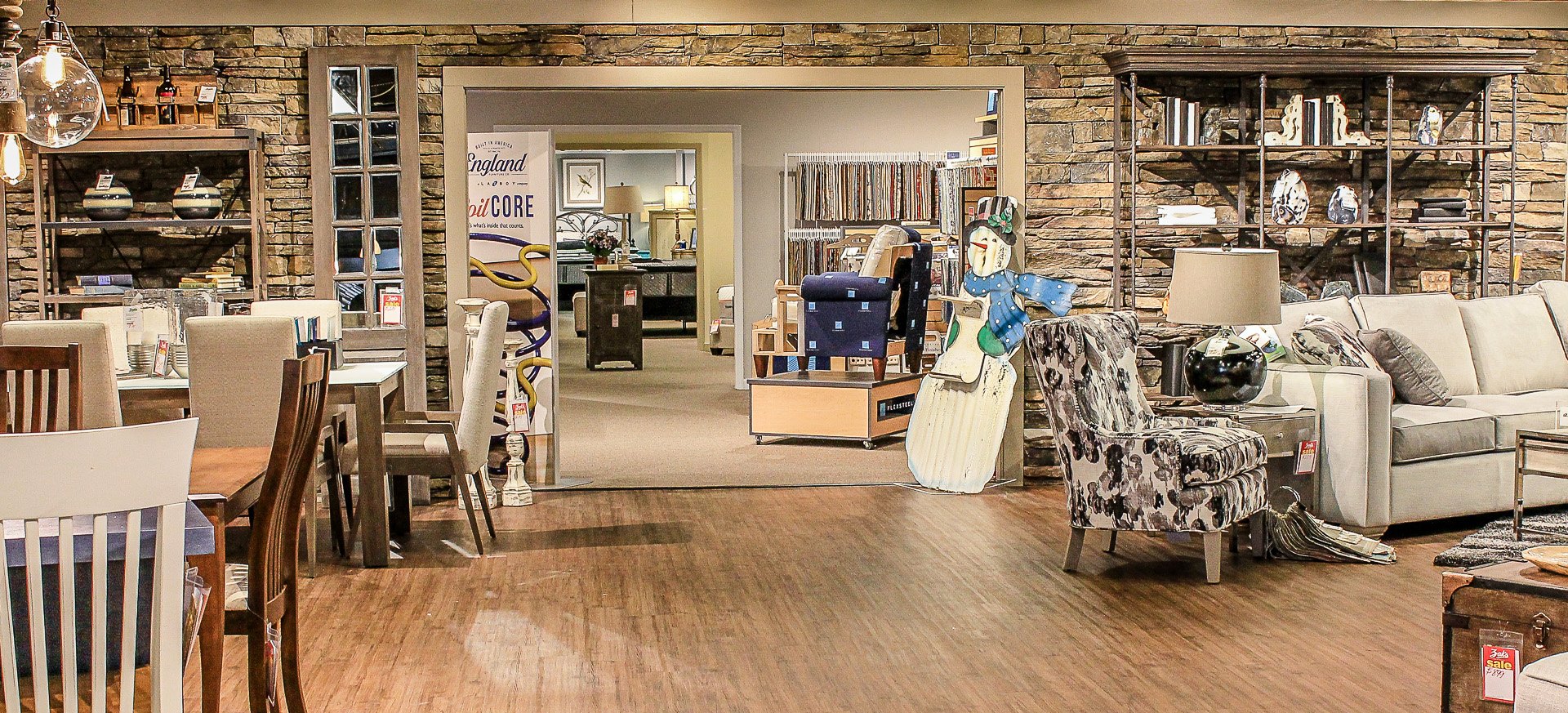 A spacious room filled with modern furniture, decorative shelves, and warm wooden flooring.