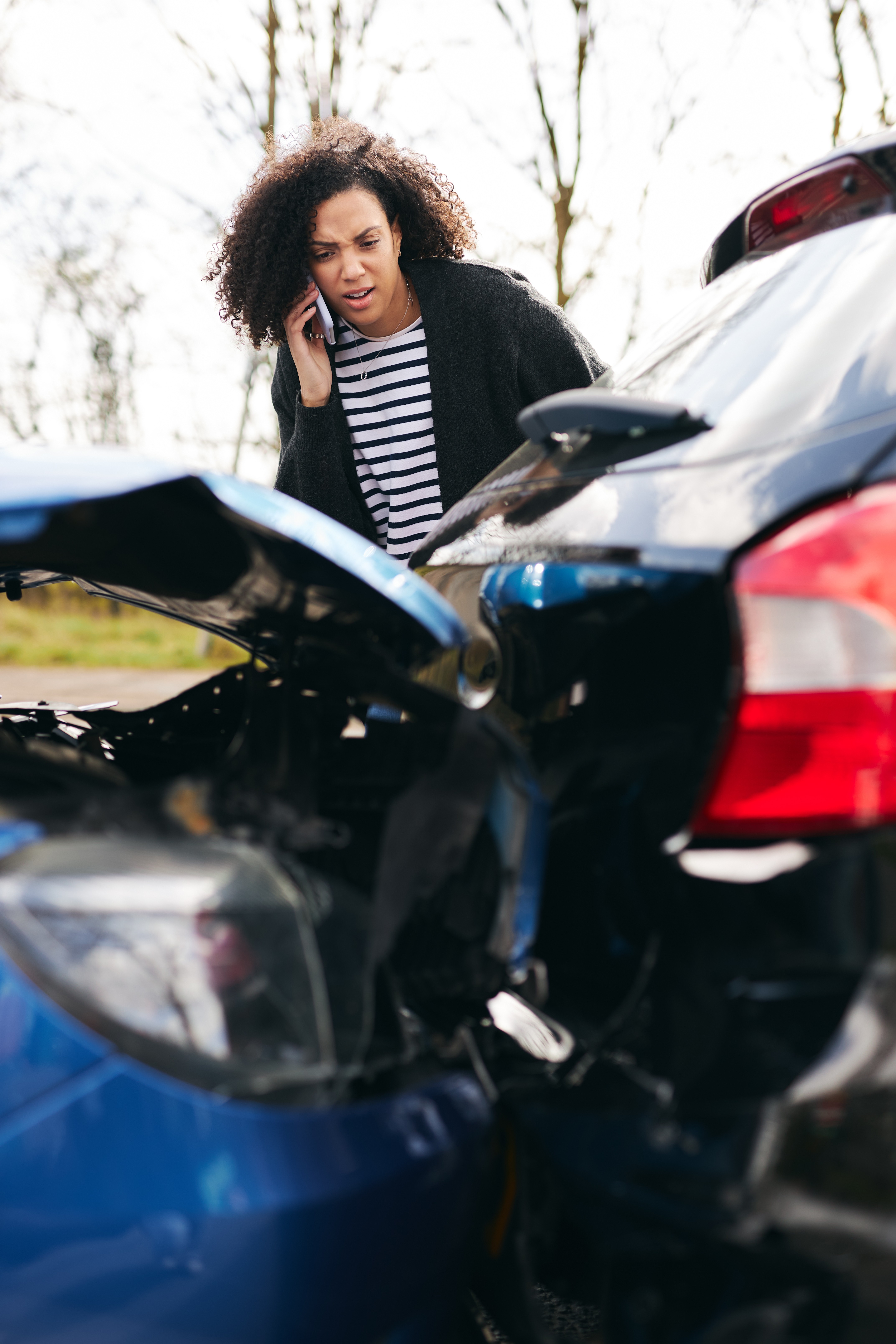 woman on phone looking at scene of a car accident