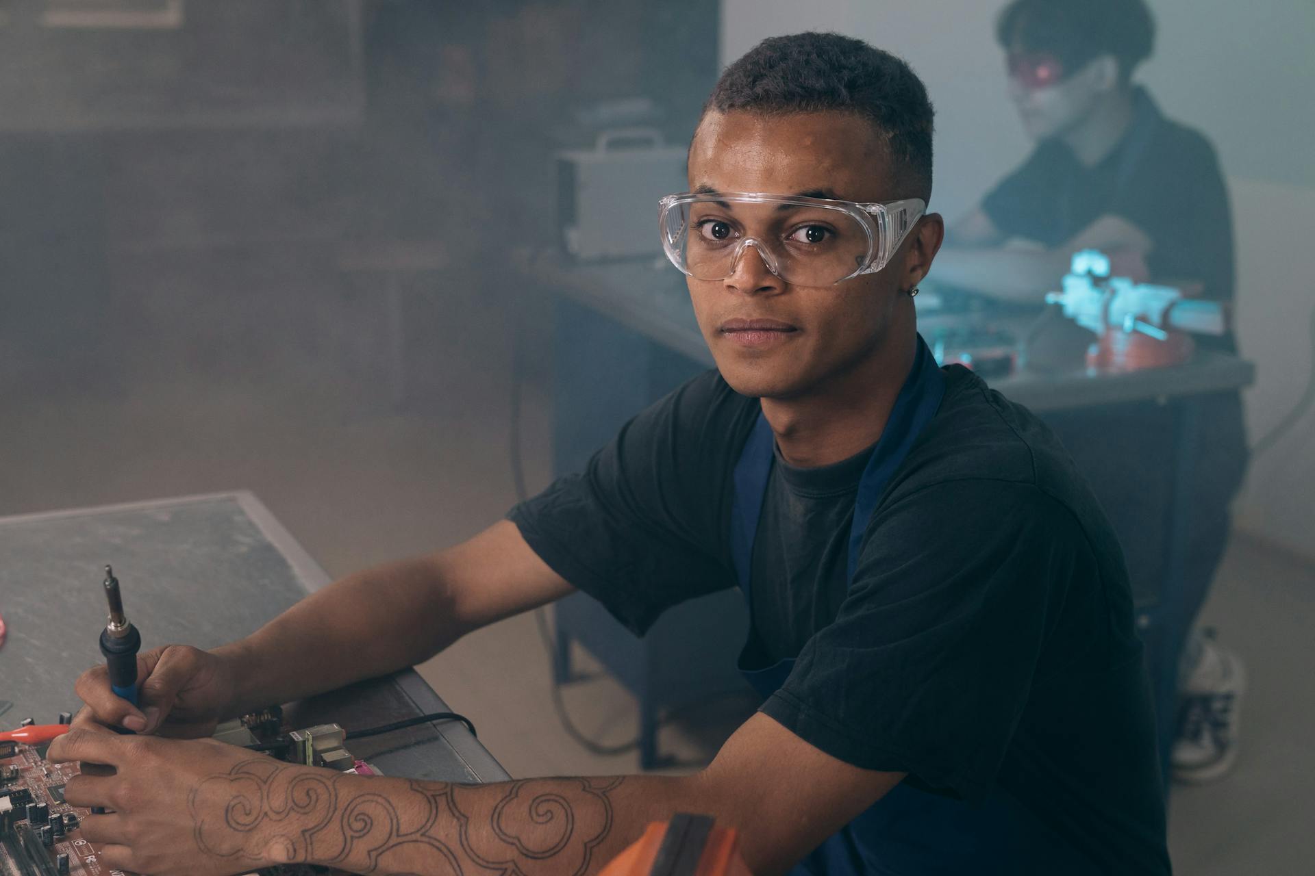 A Man using a Soldering Iron while Working on the Motherboard