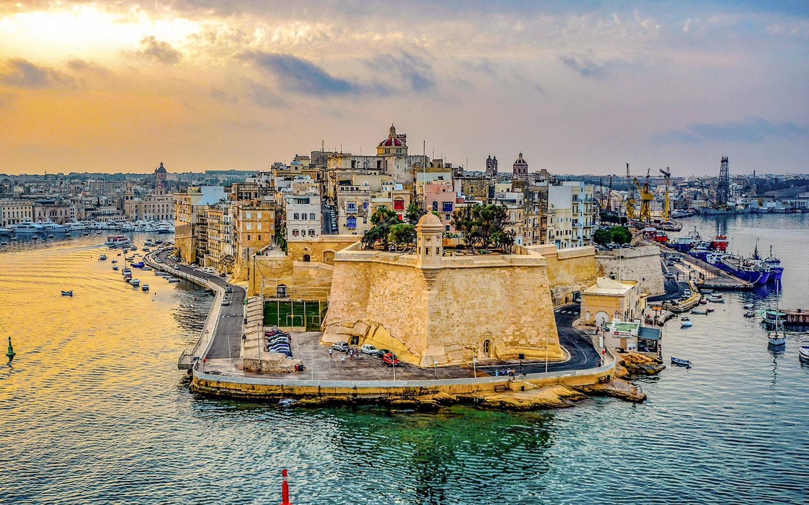 Aerial view of Valletta's historic fortifications and harbor in Malta at sunset.