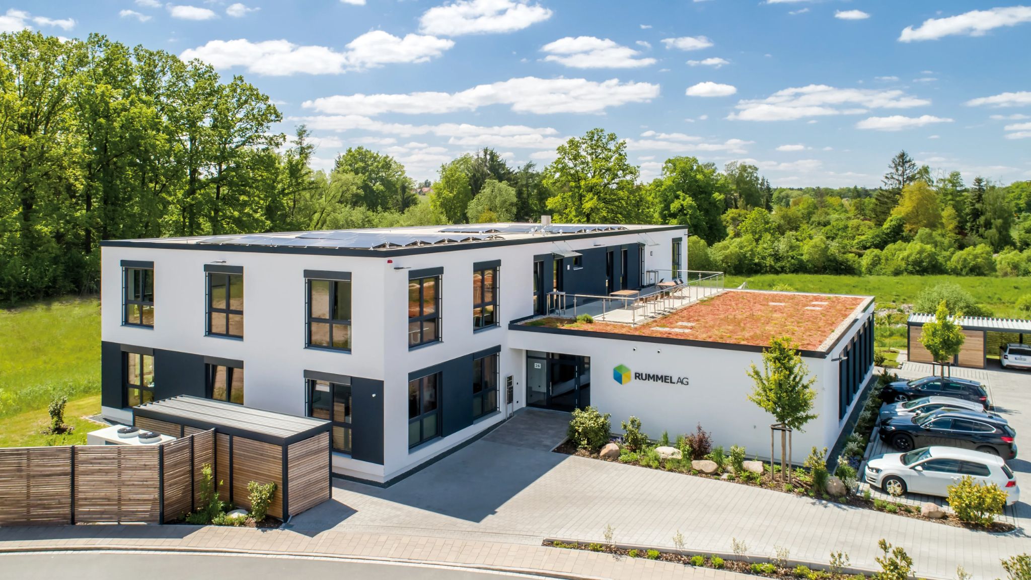 Luftaufnahme auf ein modernes Bürogebäude mit Parkplatz.