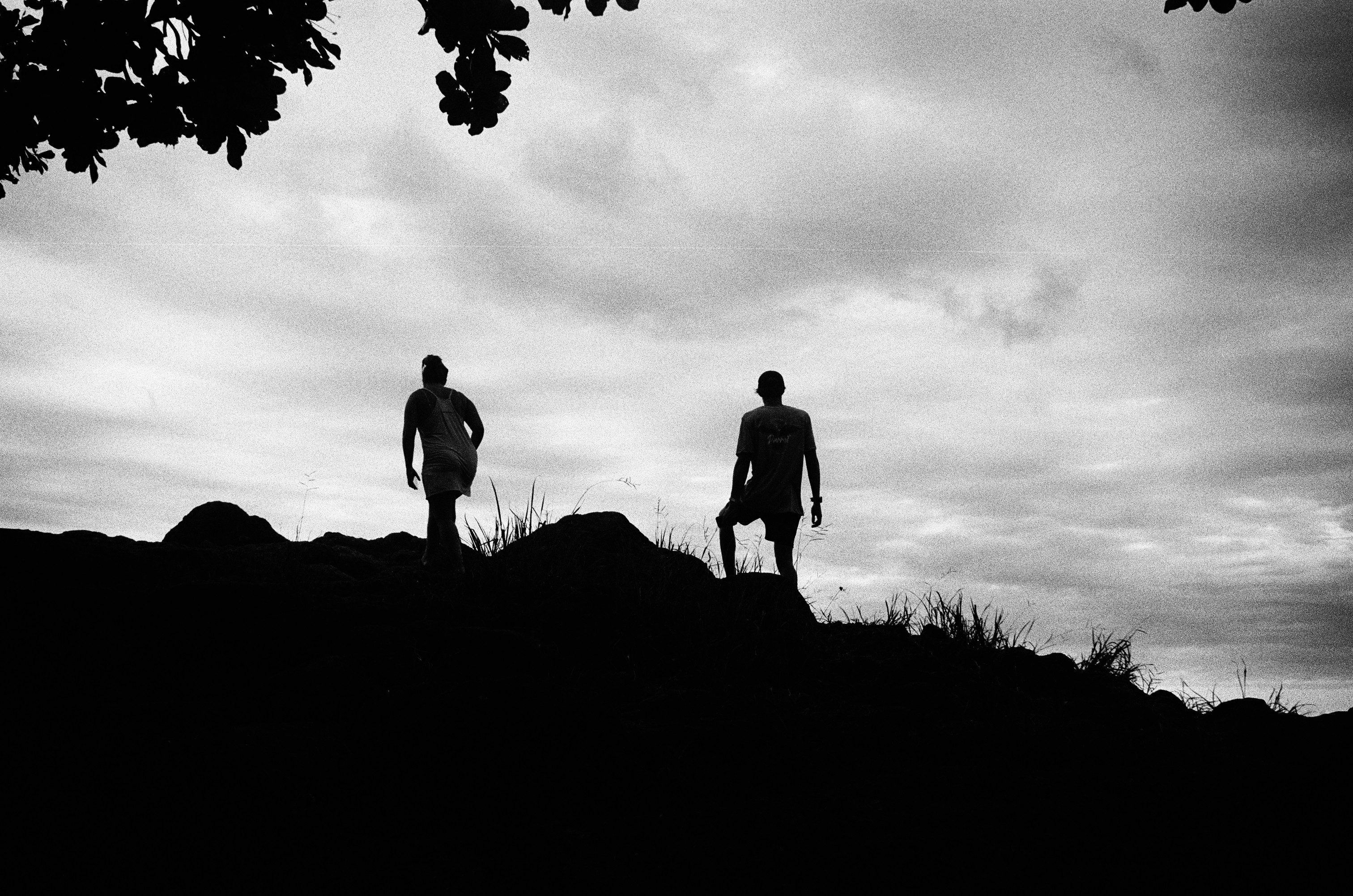 A couple climbs a rocky trail to a lookout over the ocean.