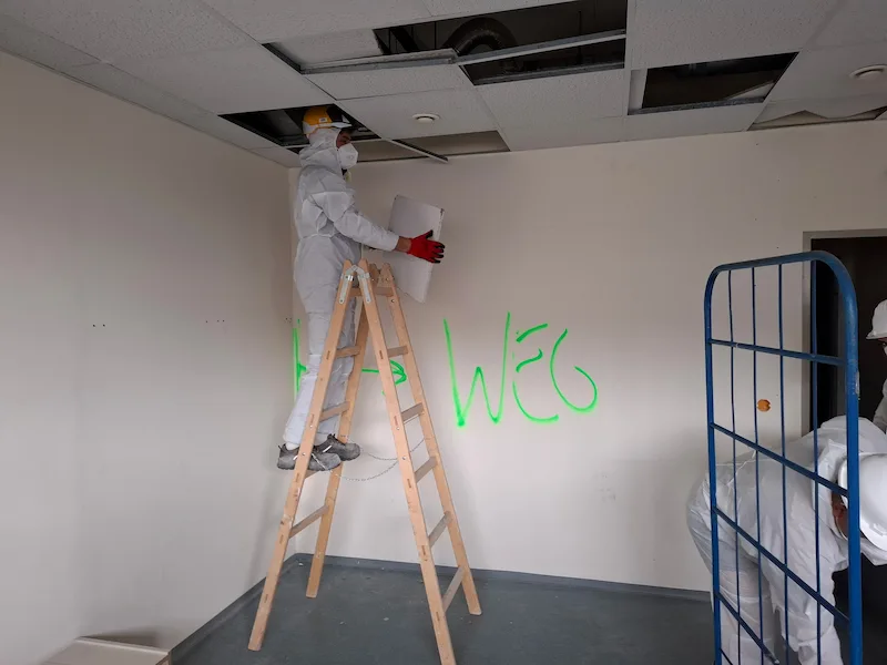 Bagger bei Abbrucharbeiten im Außenbereich beim Rückbau eines Gebäudes mit Staubentwicklung