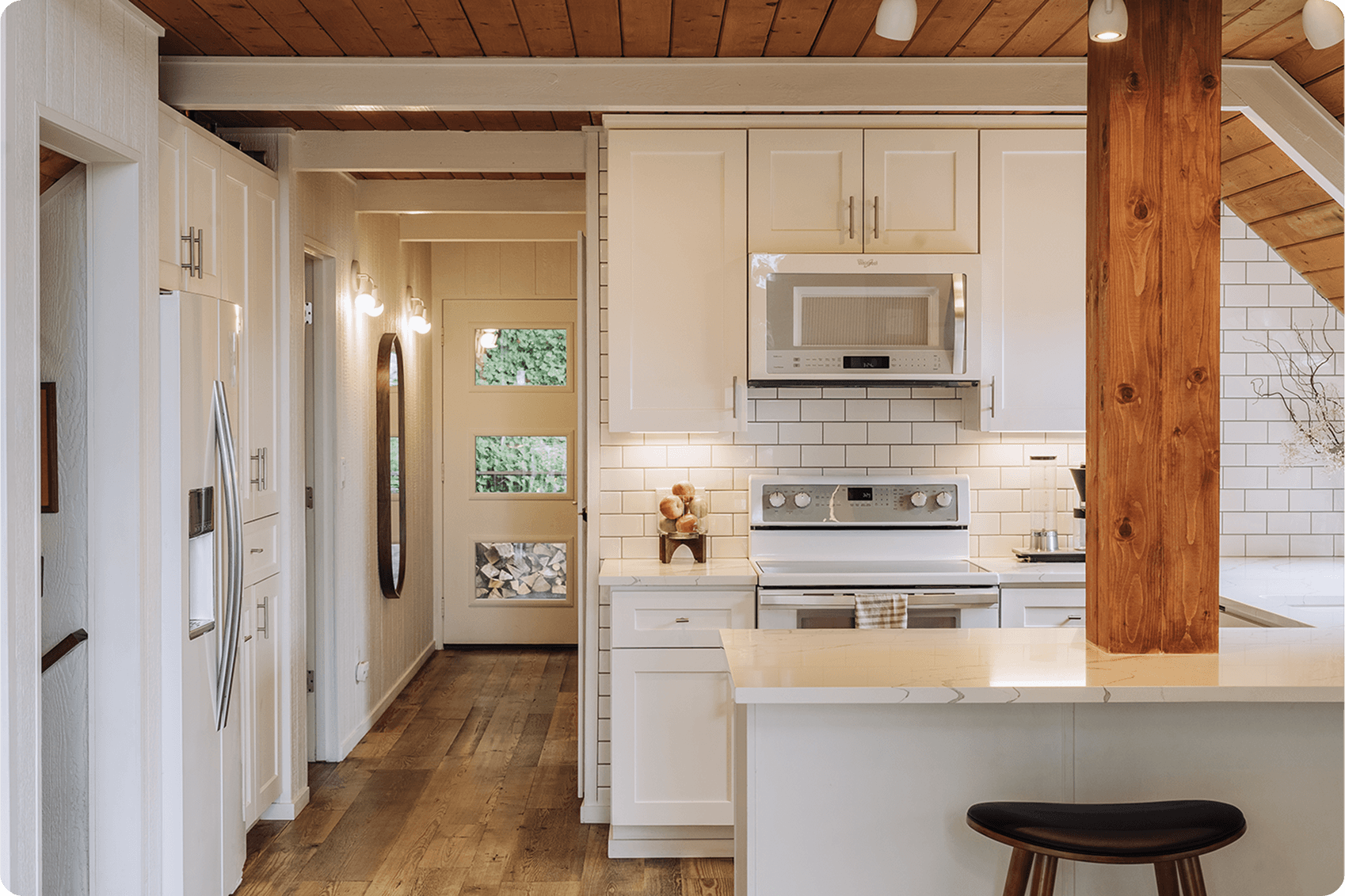 Modern bathroom with geometric patterned floor tile, white freestanding tub, brass fixtures, and white shutters
