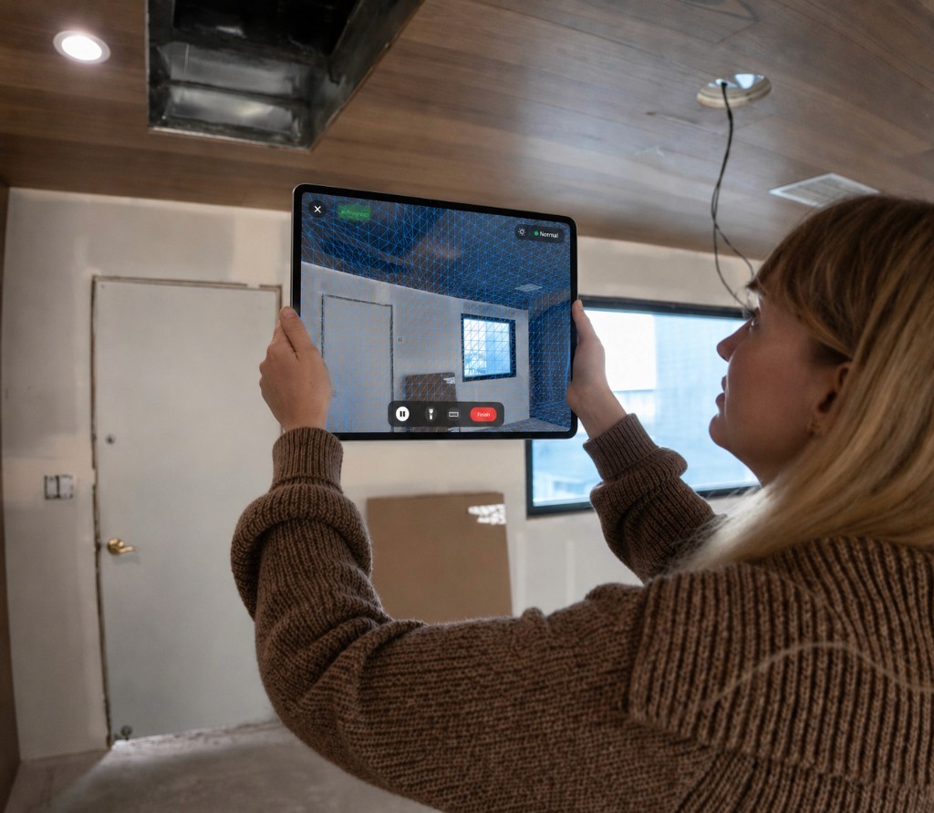 Person on site scanning a room with the Scanbrix app, live LiDAR mesh overlay on iPad