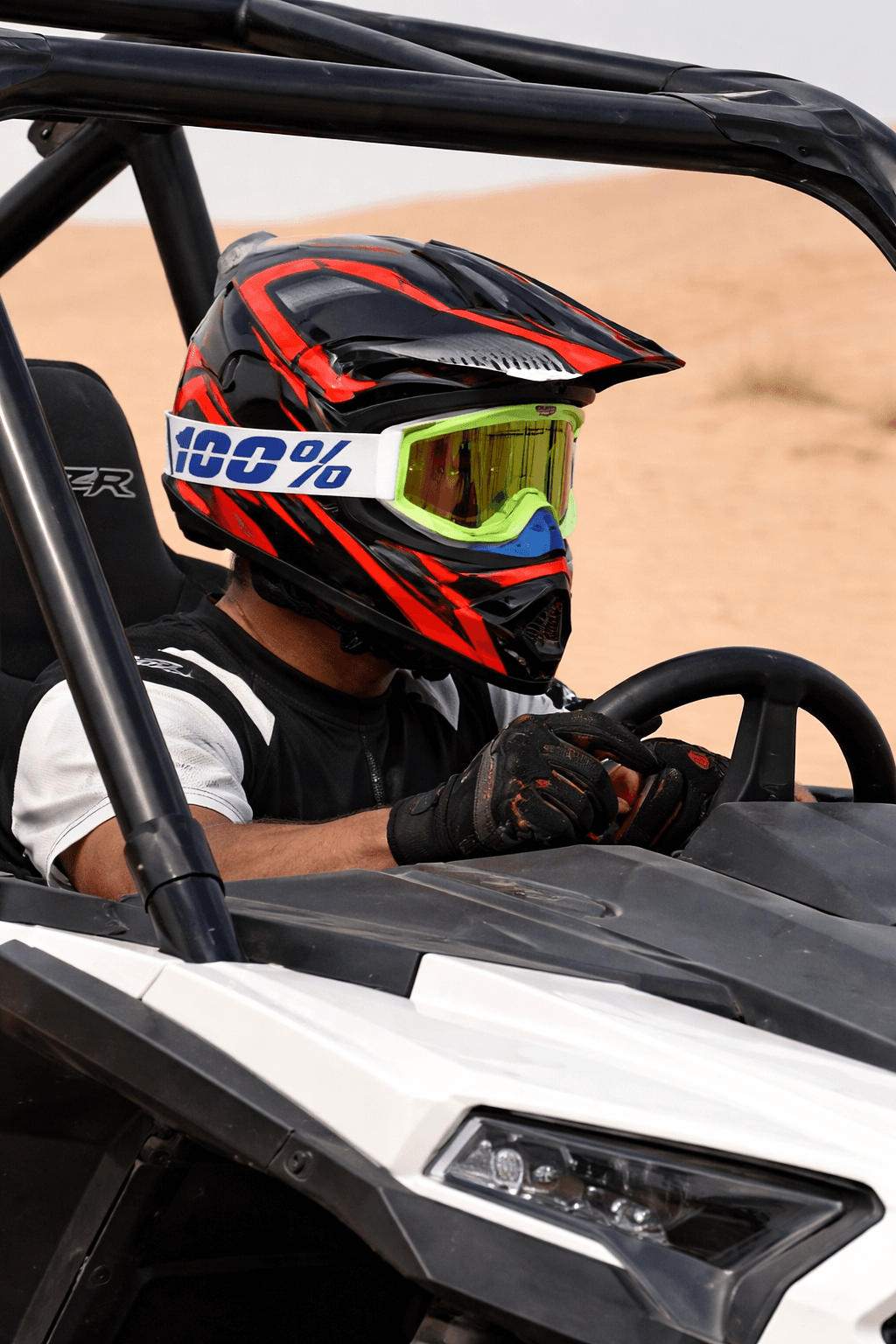 A driver navigating a high-performance Polaris RZR 1000cc through the red desert dunes of Dubai during a private Dune Quest Tours adventure.